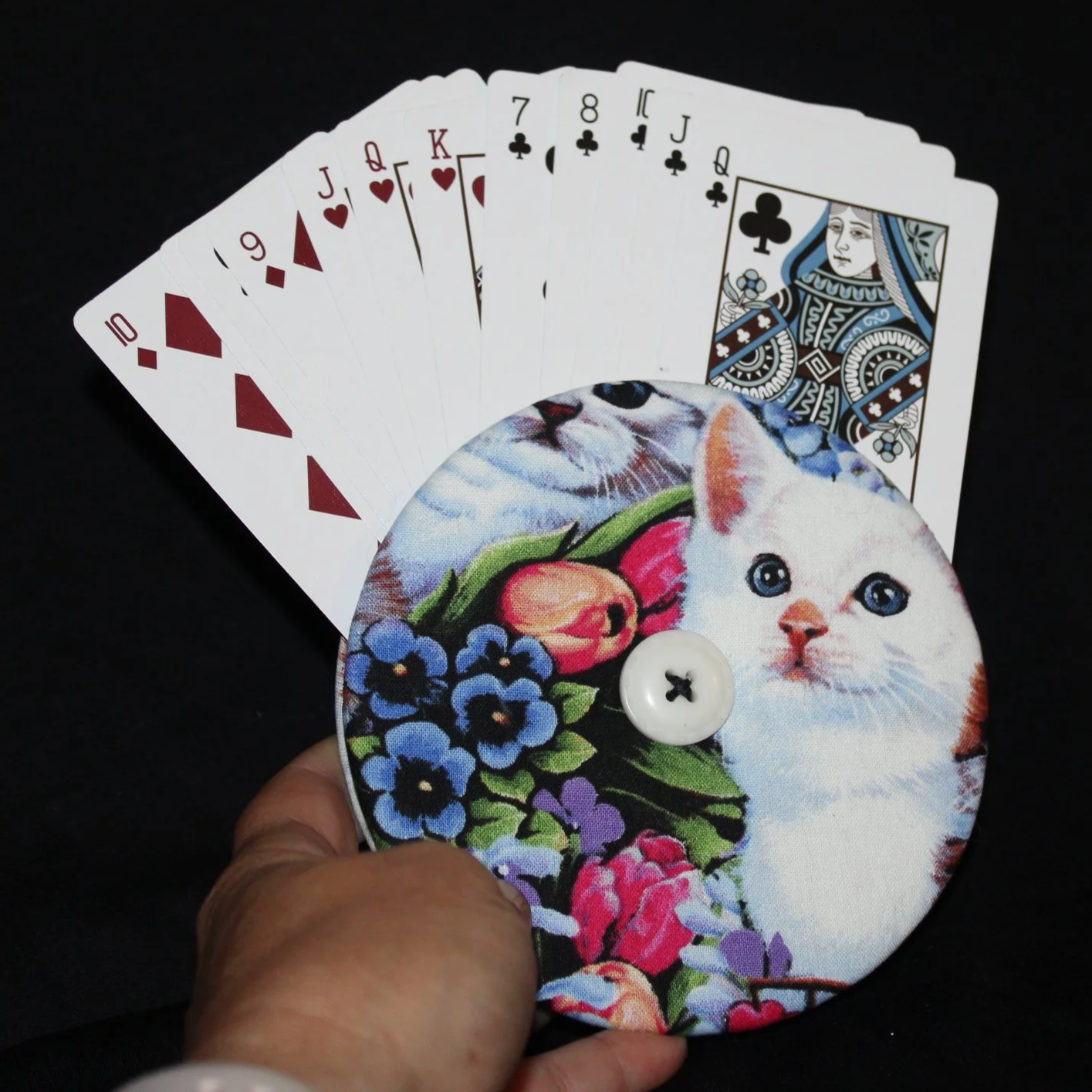 Front view of the Kitty Love Card Holder featuring an assortment of cats and floral accents shown being held in use with an assortment of playing cards.