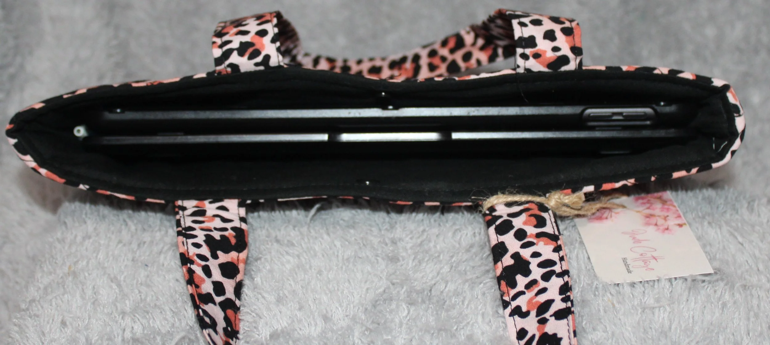 Top view of the Mia quilted animal-print sleeve with pink leopard fabric, two carry handles, a snap closure, and a tablet inserted.
