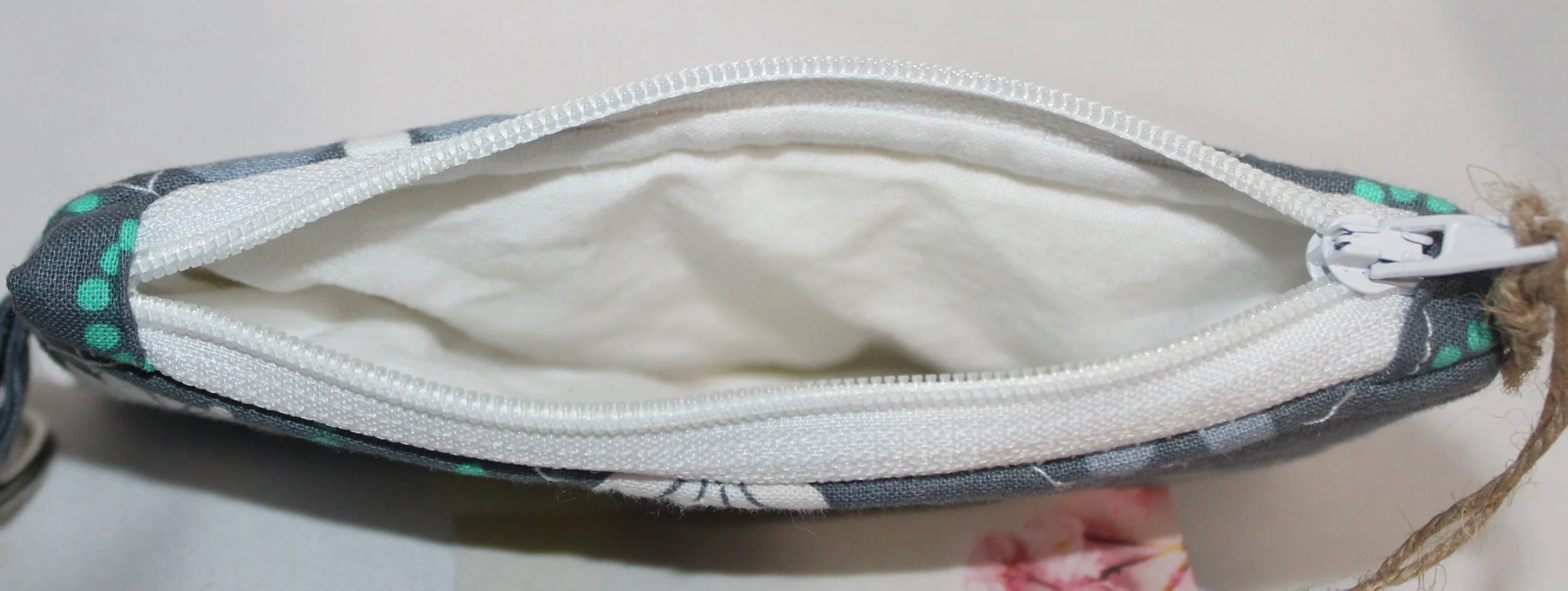 Top view of Phoebe quilted keychain wallet with soft modern pattern, zipper closure, and metal key ring showing the white lining.