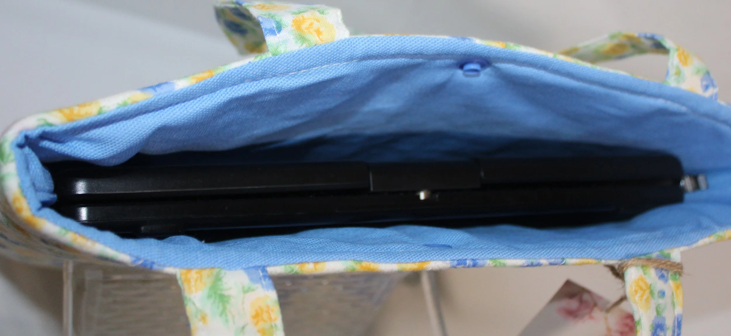 Top view of the Melody quilted tablet and book sleeve, showing a tablet inserted and the blue lining visible.