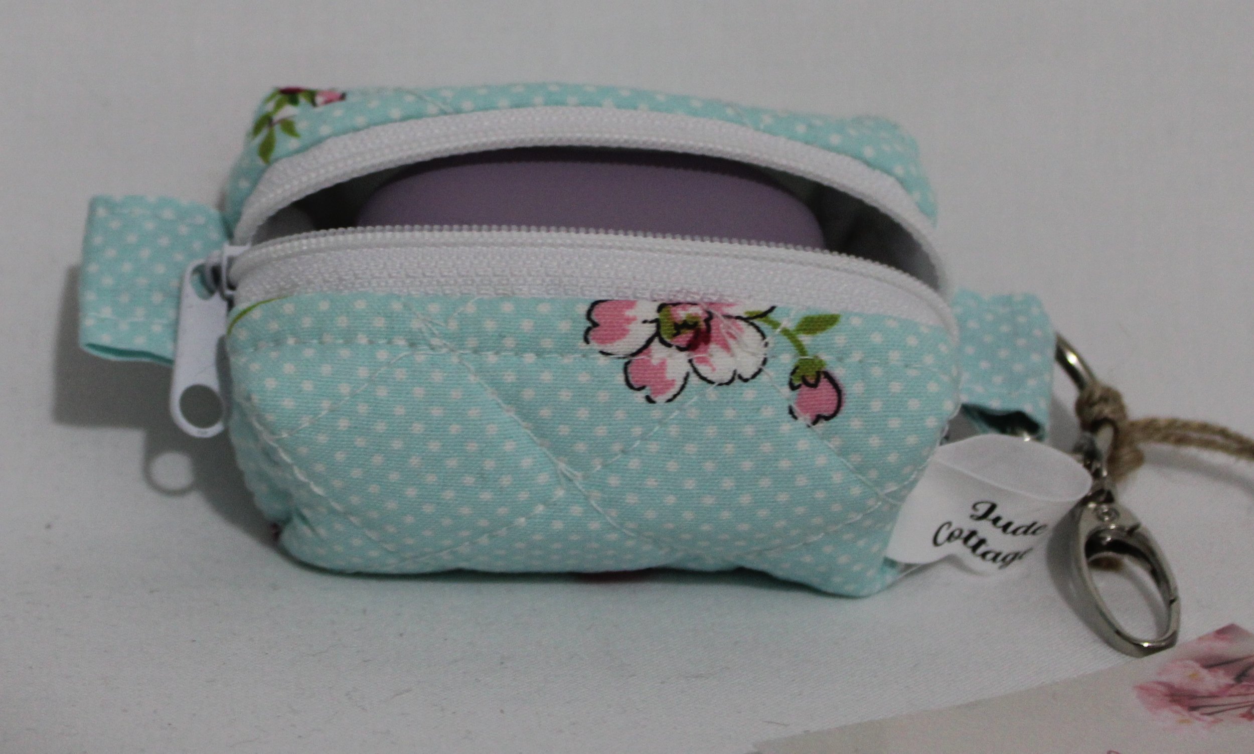Top open view of the Blossom Bag Charm featuring a light blue polka dot fabric with pink cherry blossom print shown with a J Lab earbud case inserted for sizing reference.