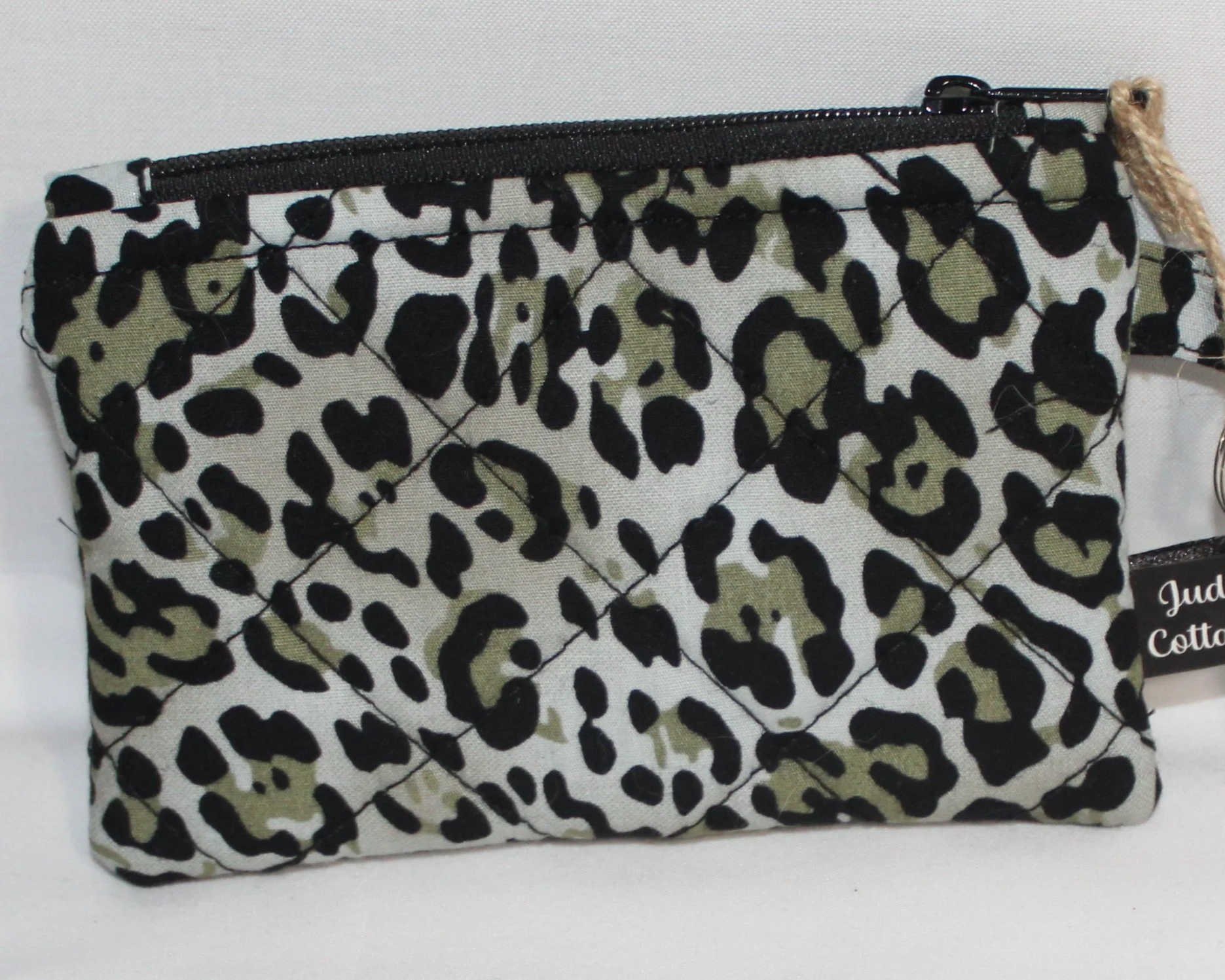 Quilted snow leopard wallet with soft animal‑print pattern, zipper closure, and metal key ring.
