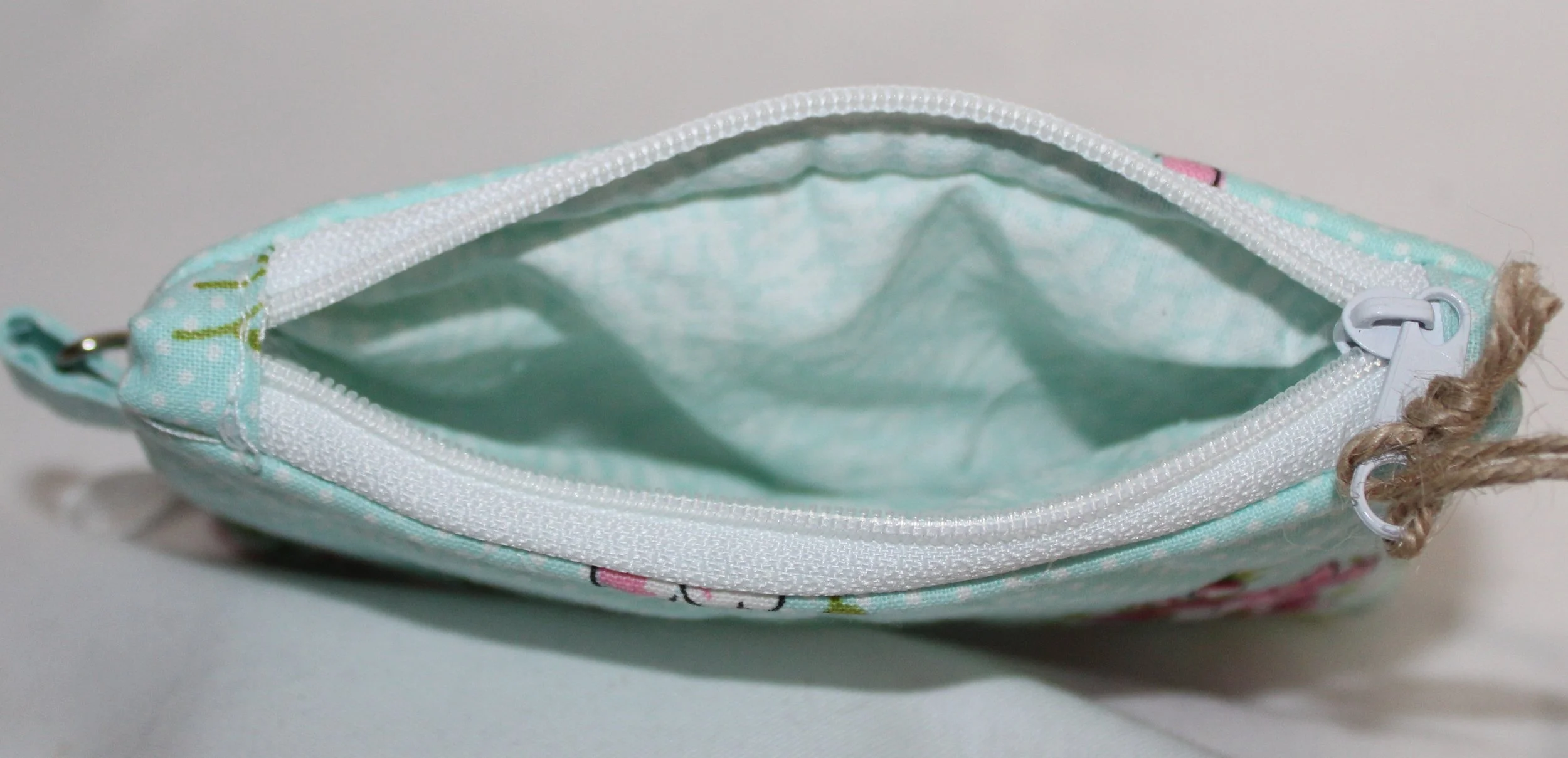 Top view quilted cherry blossom keychain wallet with blue background pattern, zipper closure, and metal key ring.