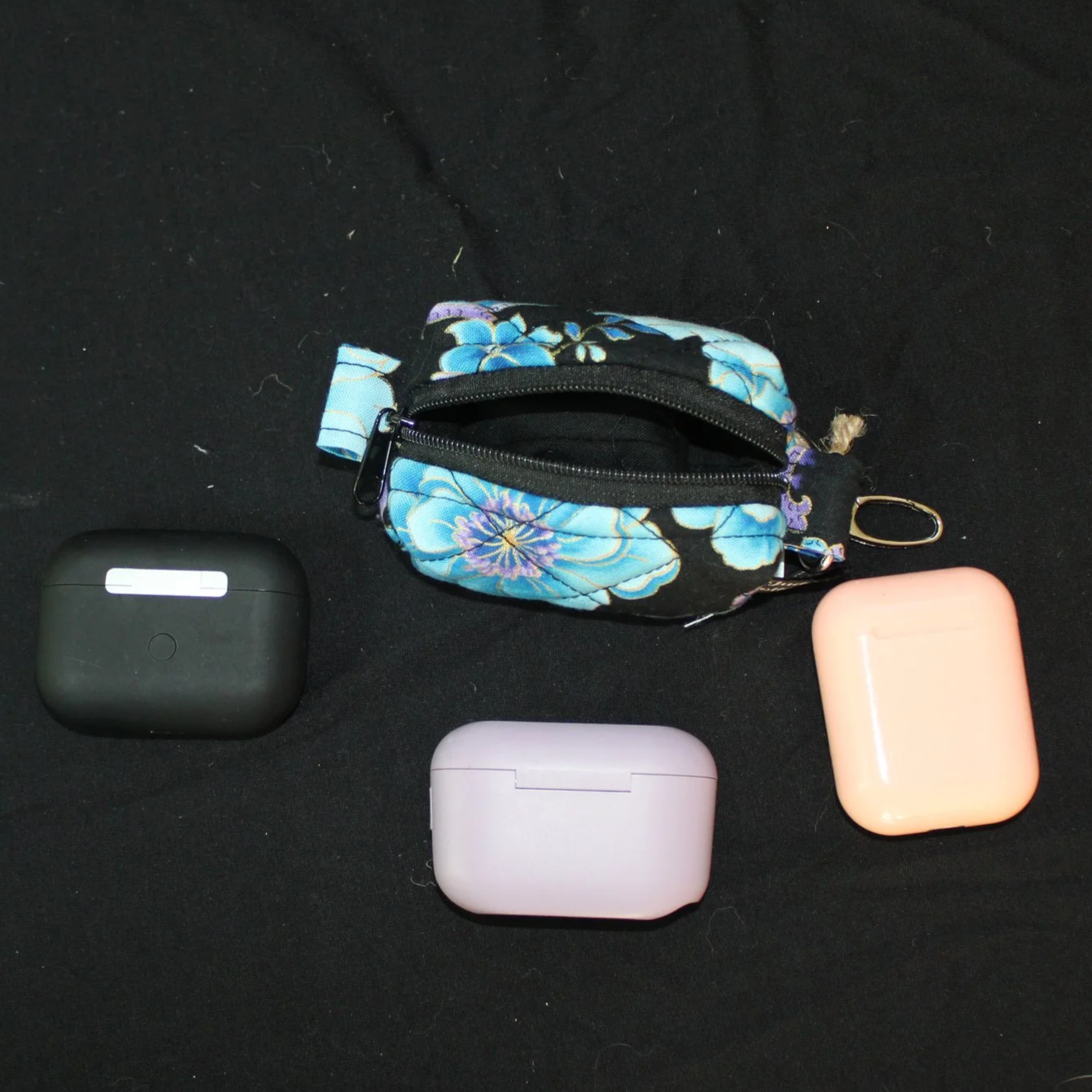 Top view of open zippered Twilight Paisley Bag Charm displaying black lining and shown with J Lab  and air pod earbud cases for sizing reference.