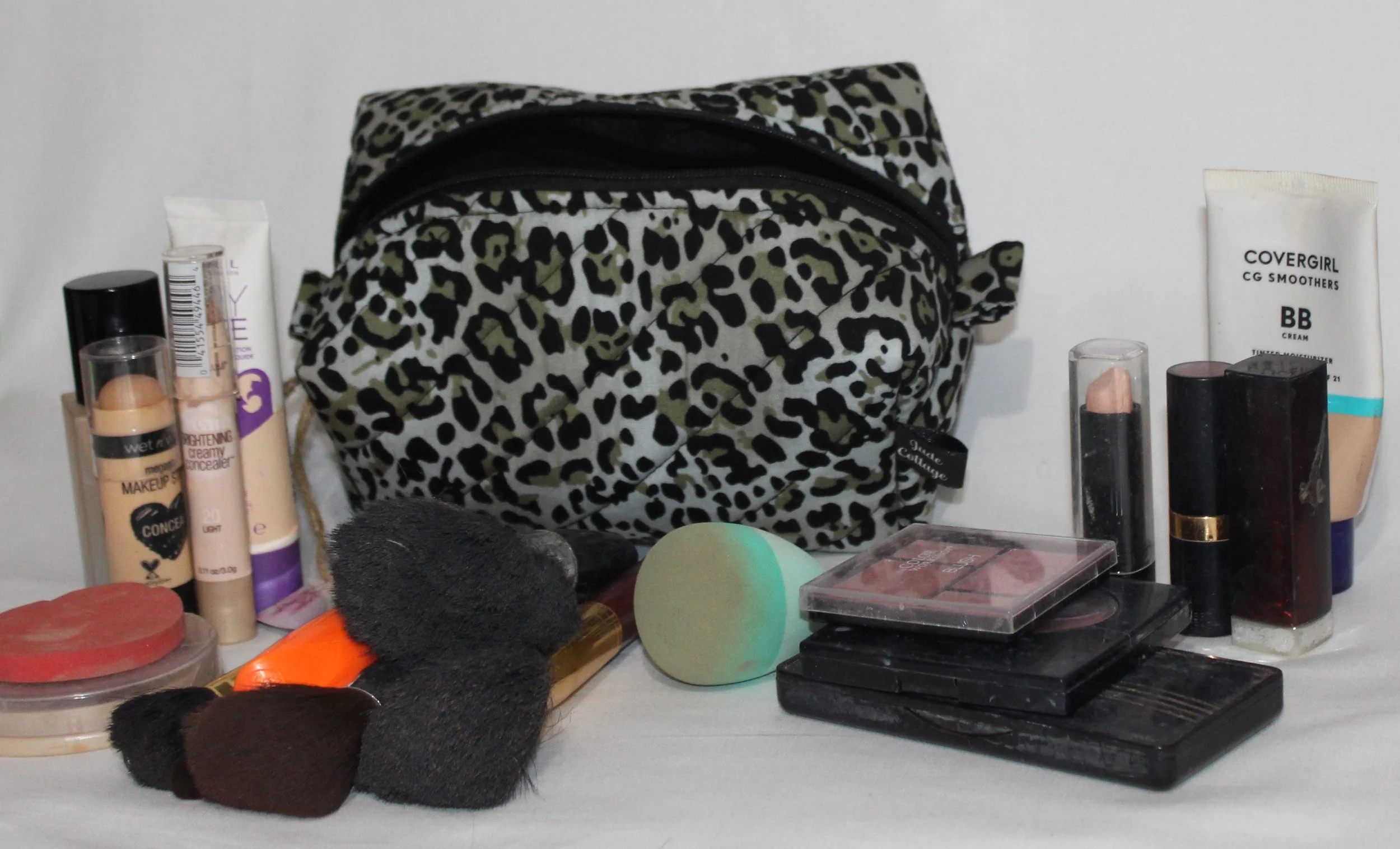 Angled front view of the Diana quilted travel pouch shown with cosmetics to illustrate size.