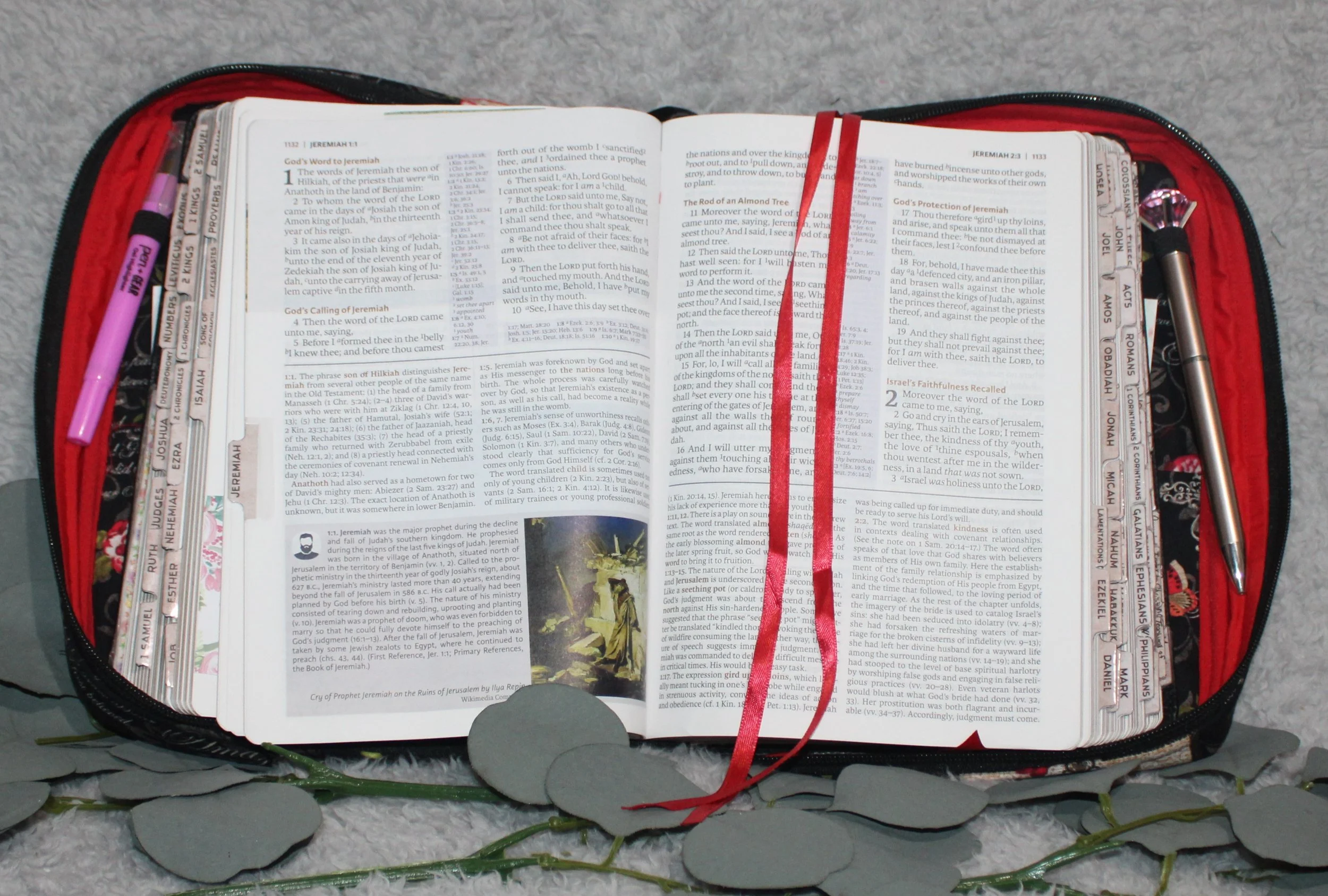 Amazing Grace Bible case opened to show an open Bible with red ribbon bookmarks, tabbed pages, and writing tools stored in the attached pen loops.