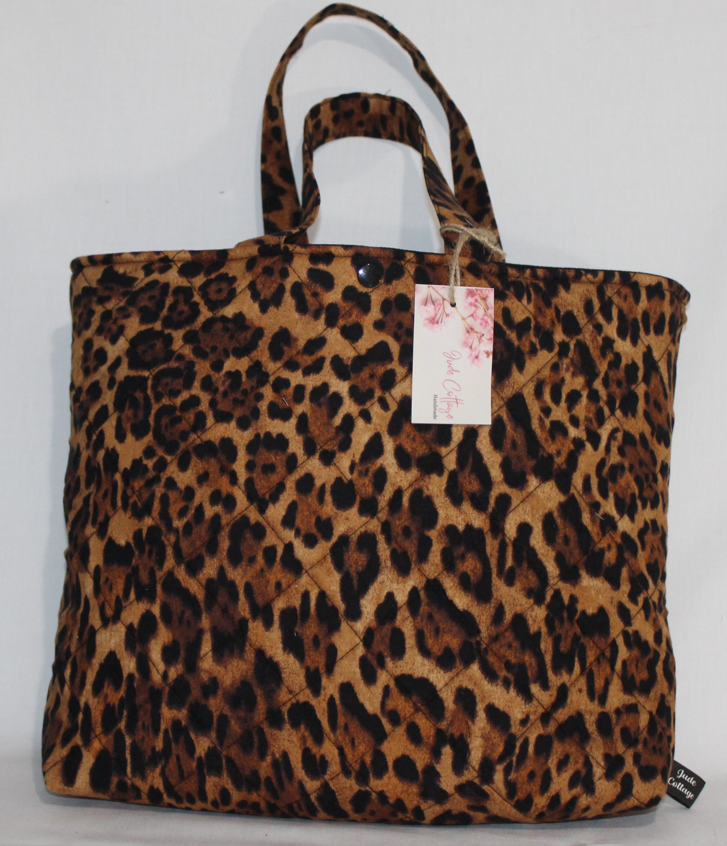 Front view of the Lyra quilted Bible sleeve with leopard‑print fabric and two carry handles.