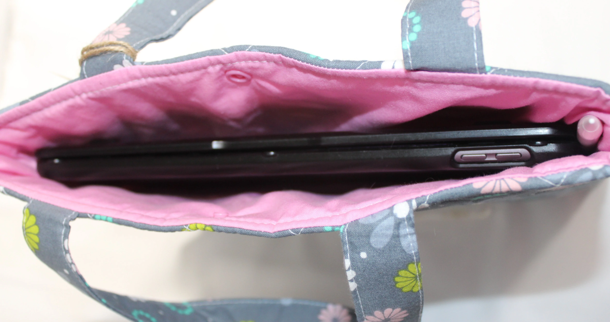 Top view of the Phobe quilted tablet and book sleeve, showing a tablet inserted and the pink lining visible.