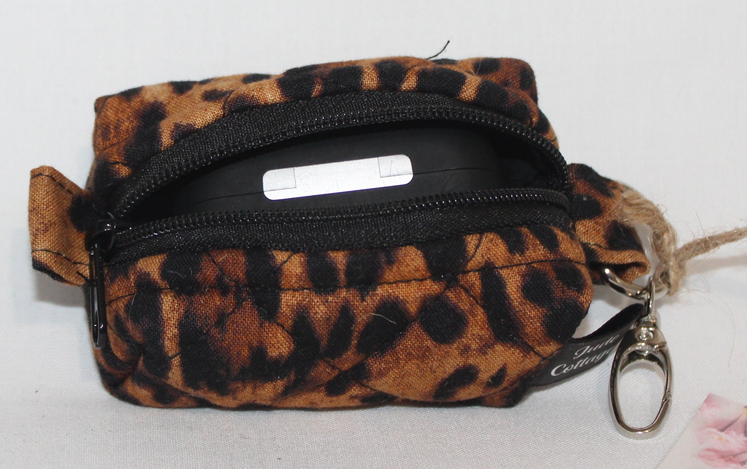 Top open view of the Lyra Bag Charm featuring a leopard print fabric and shown with an Airpod Pro case inserted for sizing reference.