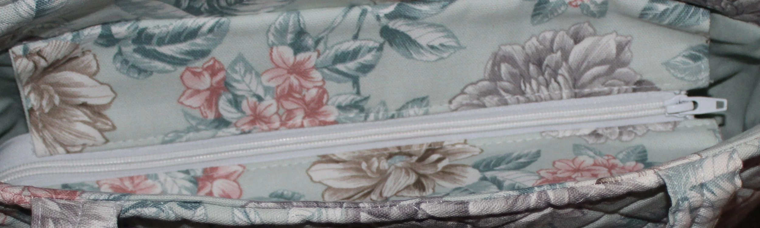Top view of the Joelle quilted tote in mint green fabric with a pink and gray floral pattern, shown with the recessed zipper fully closed.