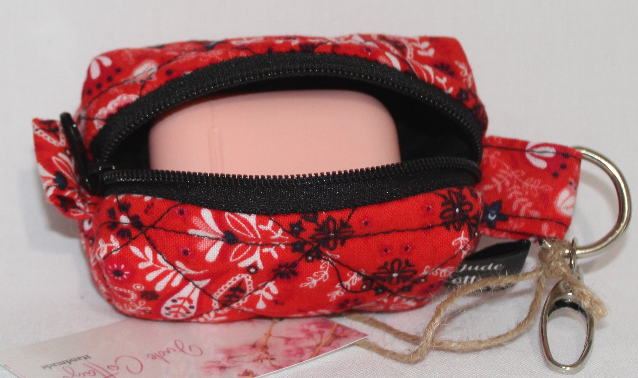 Top open view of the Freedom Red Bag Charm featuring red background with floral and paisley print fabric, shown with an Airpod earbud case inserted to demonstrate fit.