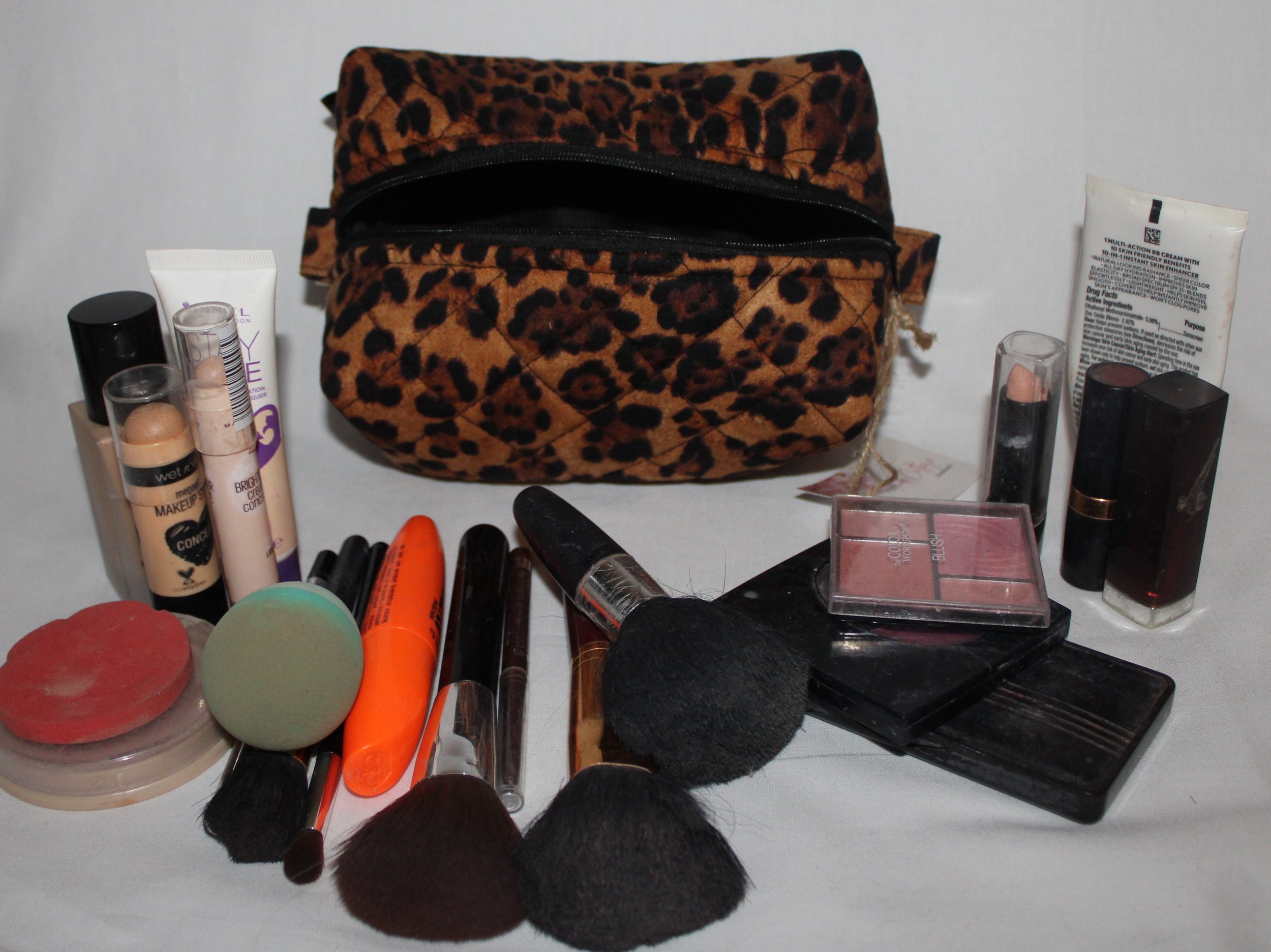 Top empty view of the large Lyra quilted travel pouch in brown and black leopard fabric with assorted cosmetics arranged around it.