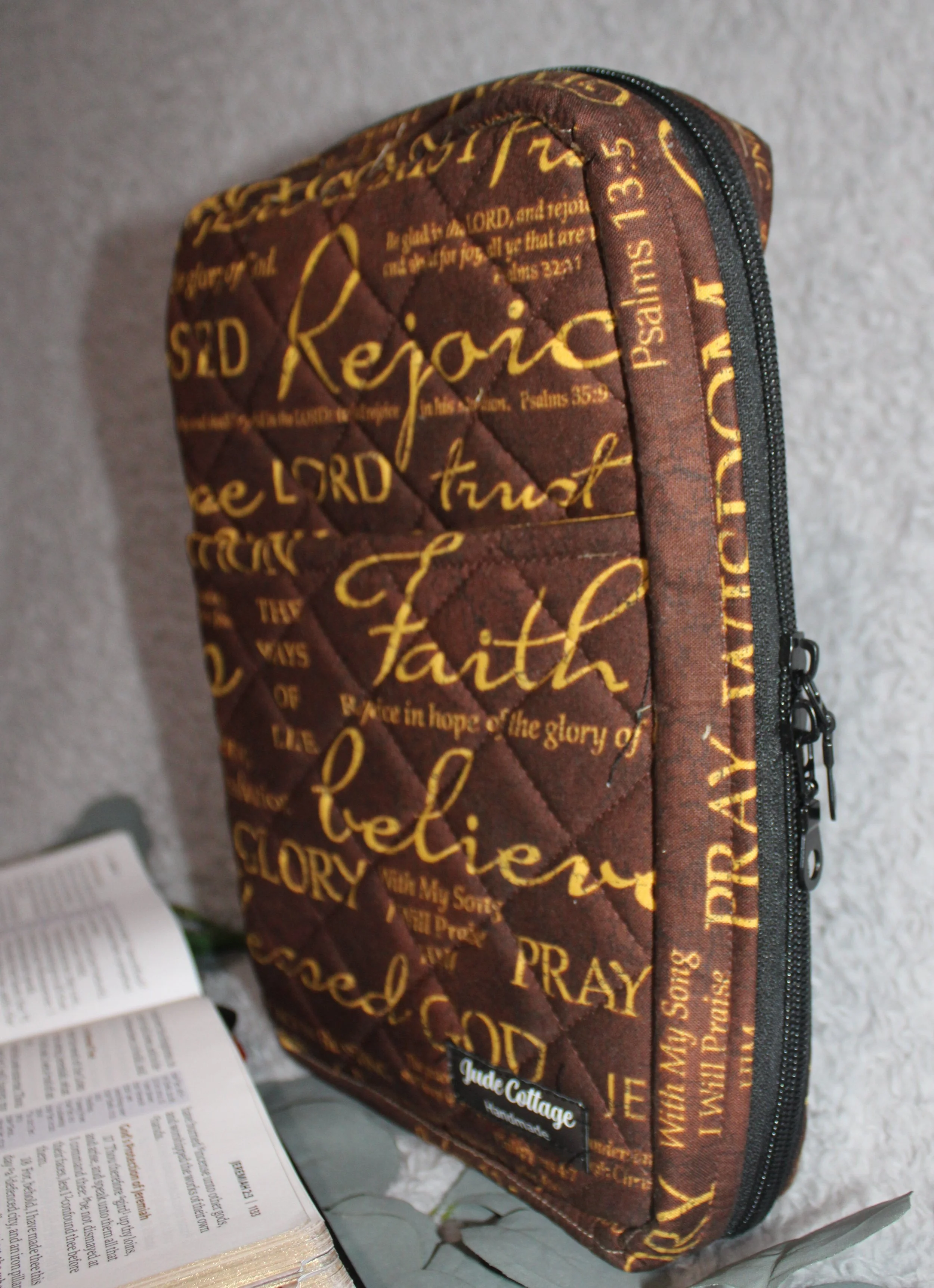 Side view of the Rejoice Study Bible Case showing the double‑zip closure and the brown quilted exterior with gold inspirational wording visible along the edge.