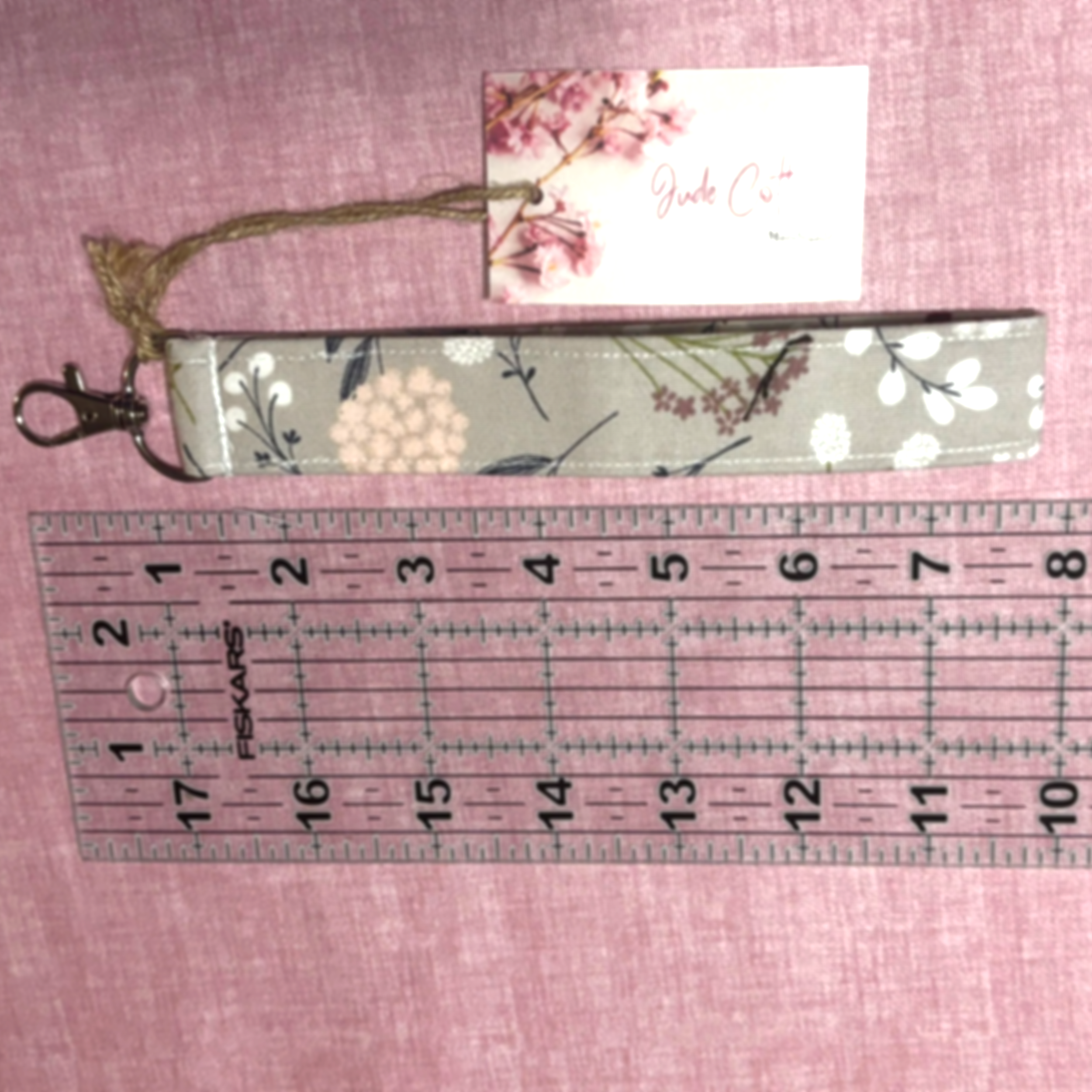 Dandelion Field Wristlet shown on a pink background below a ruler to demonstrate length.