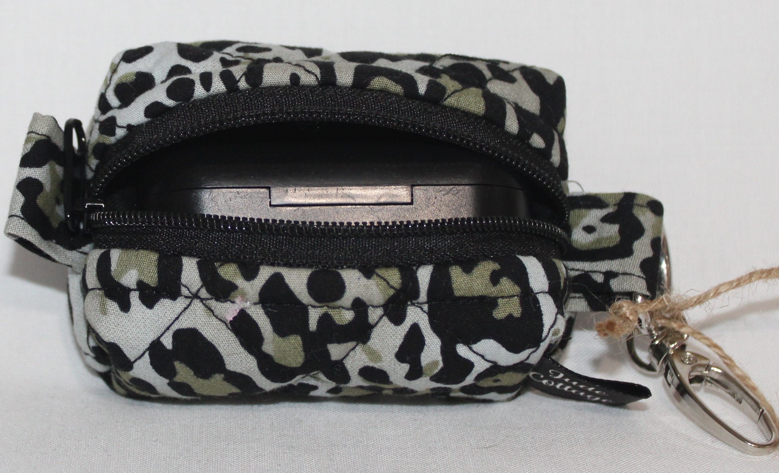 Open top view of the Diana Bag Charm featuring snow leopard print showing a set of J Lab earbuds inserted for sizing.