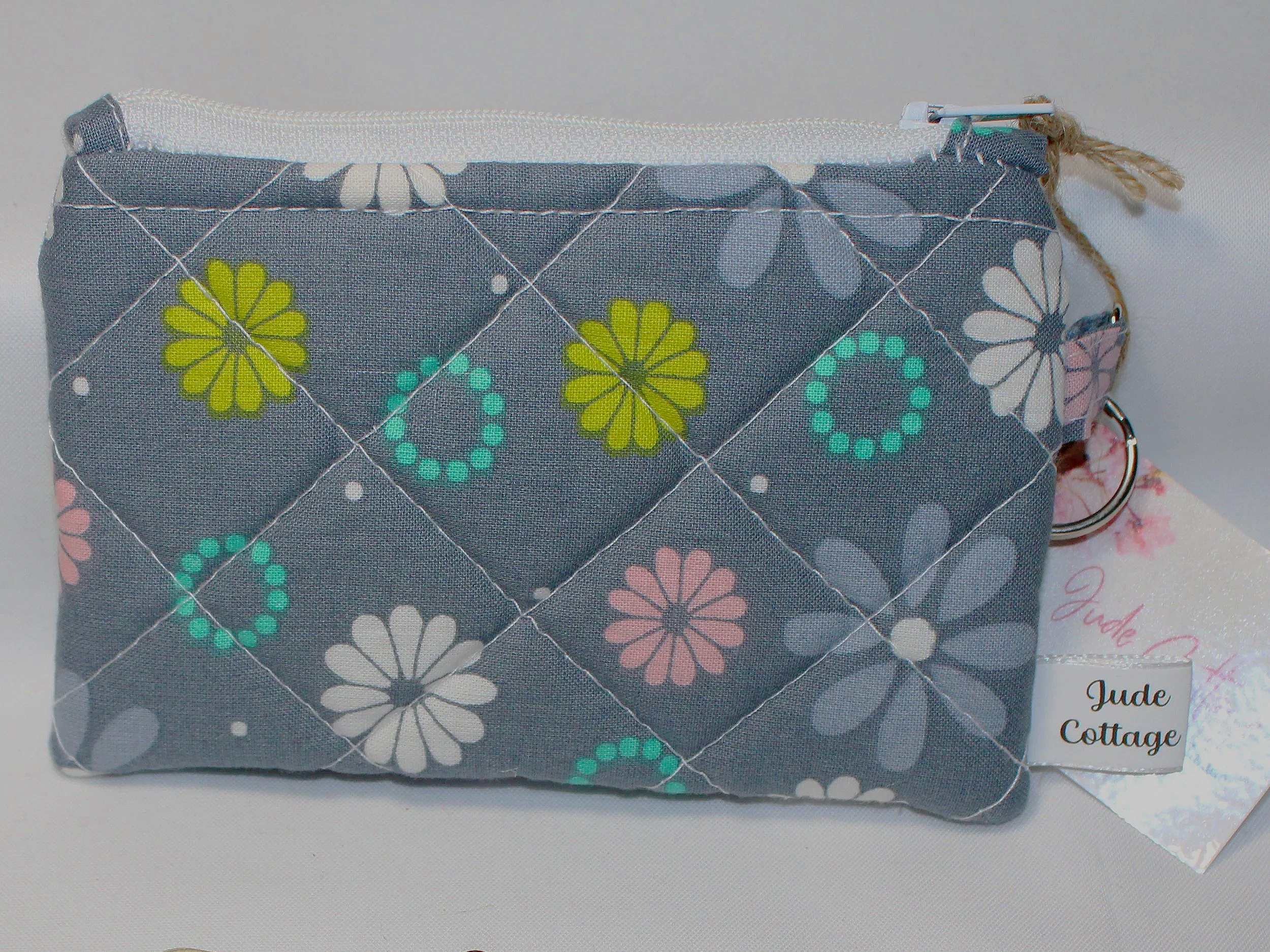 Close-up view of the Phoebe quilted keychain wallet with soft modern pattern, zipper closure, and metal key ring.