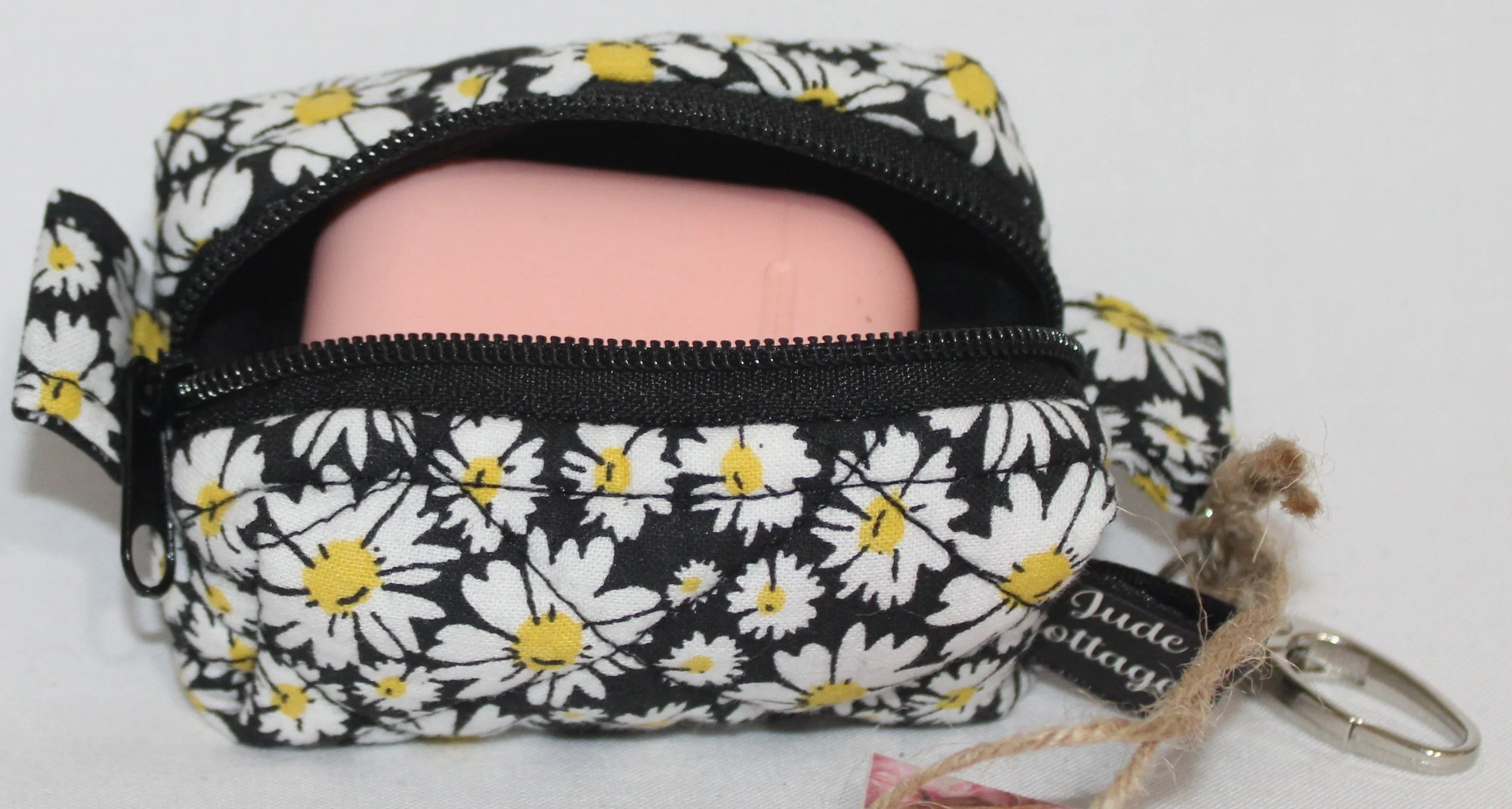 Top open view of the Ditzy Daisy Bag Charm showing zip enclosure and an Airpod case inserted for size reference.