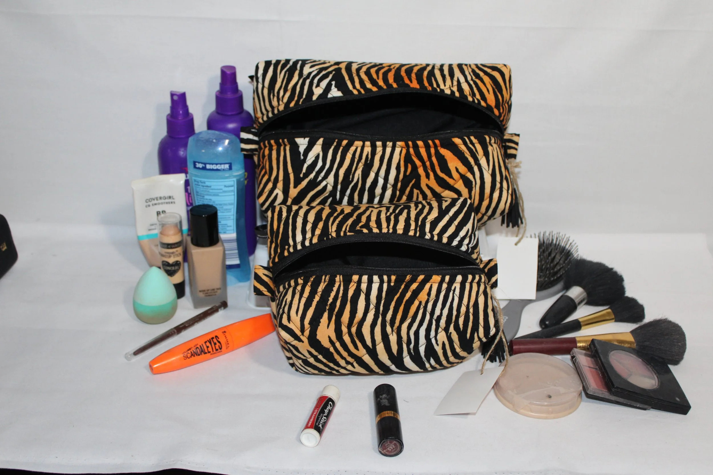 Angled front view of both large and small Zara tiger‑print quilted travel bag with black zipper open showing black lining.