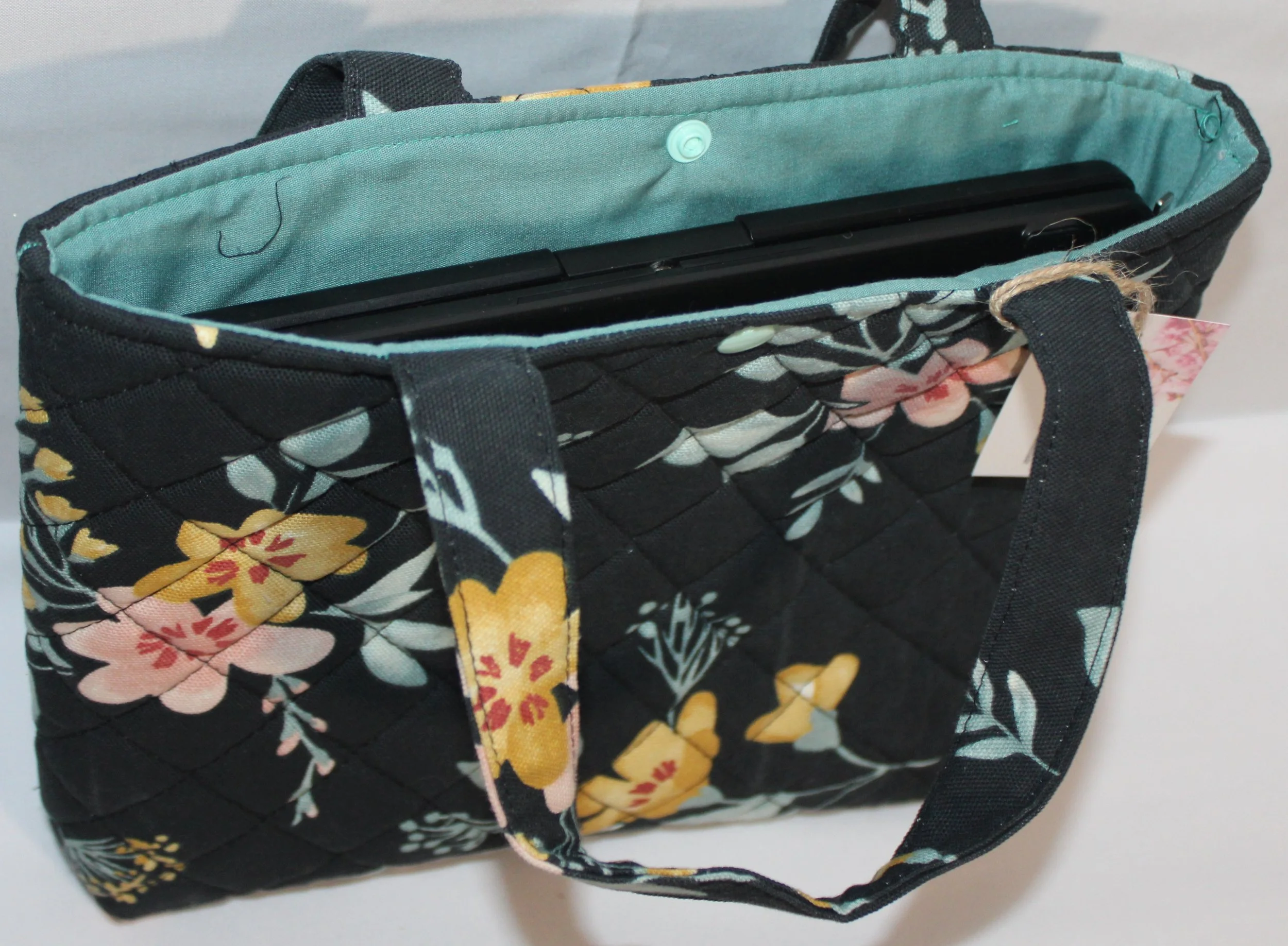 Top view of Twyla quilted floral sleeve with tablet inserted showing top snap closure.