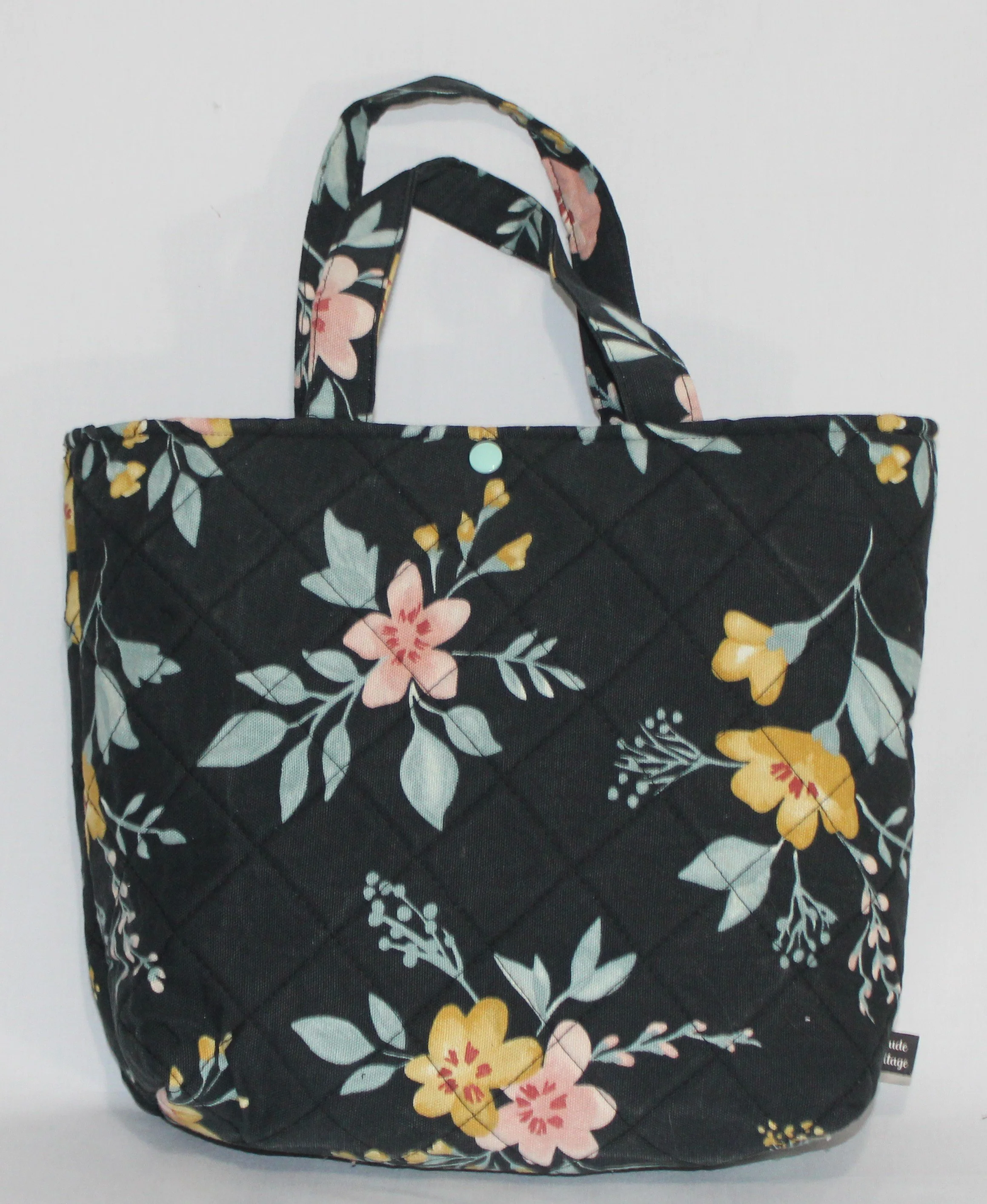 Front view of the Twyla quilted Bible sleeve showing two handles and snap closure.