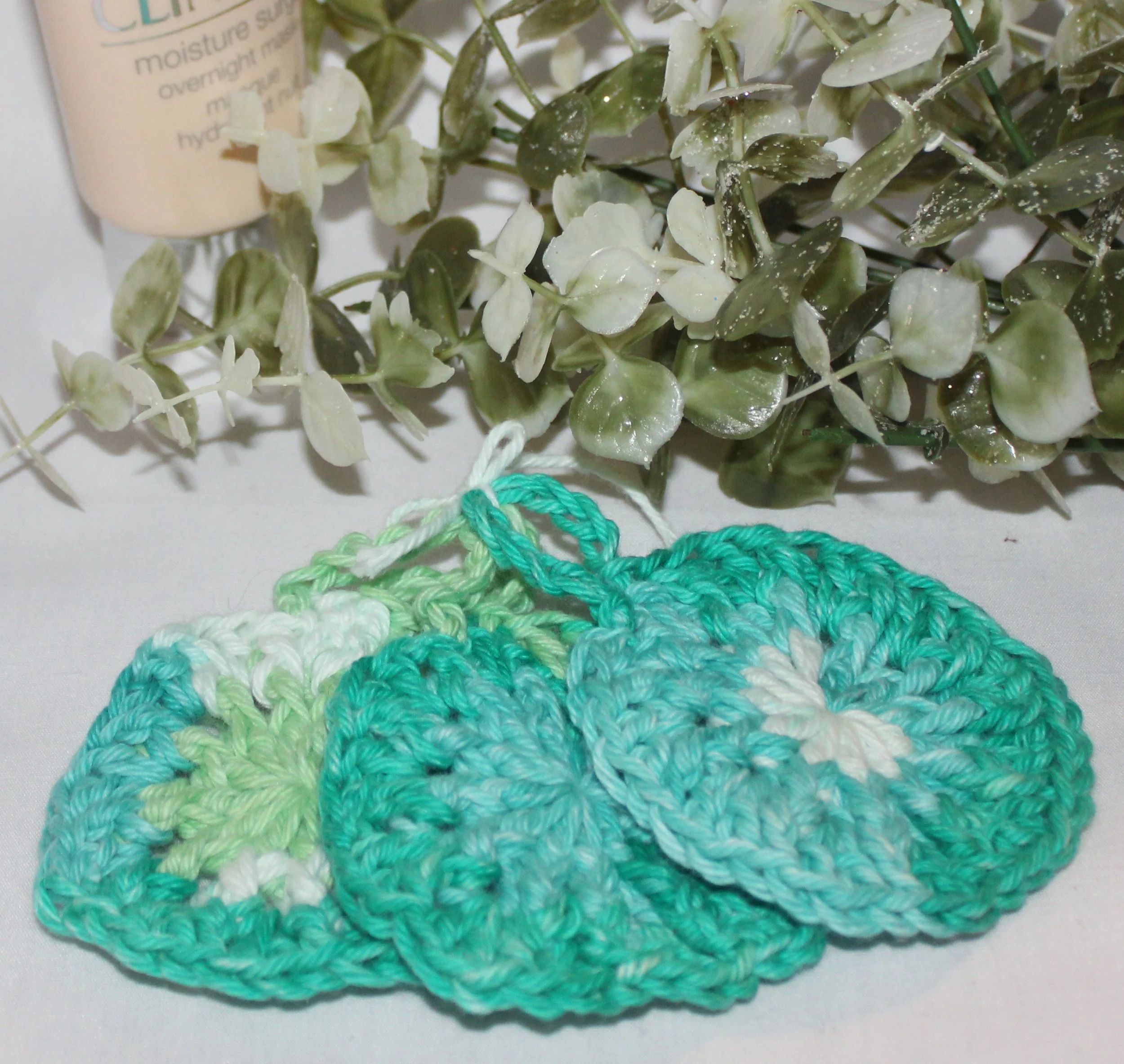 Set of handmade crocheted face scrubbies in assorted shades of green colors, arranged on a flat surface and show the texture.