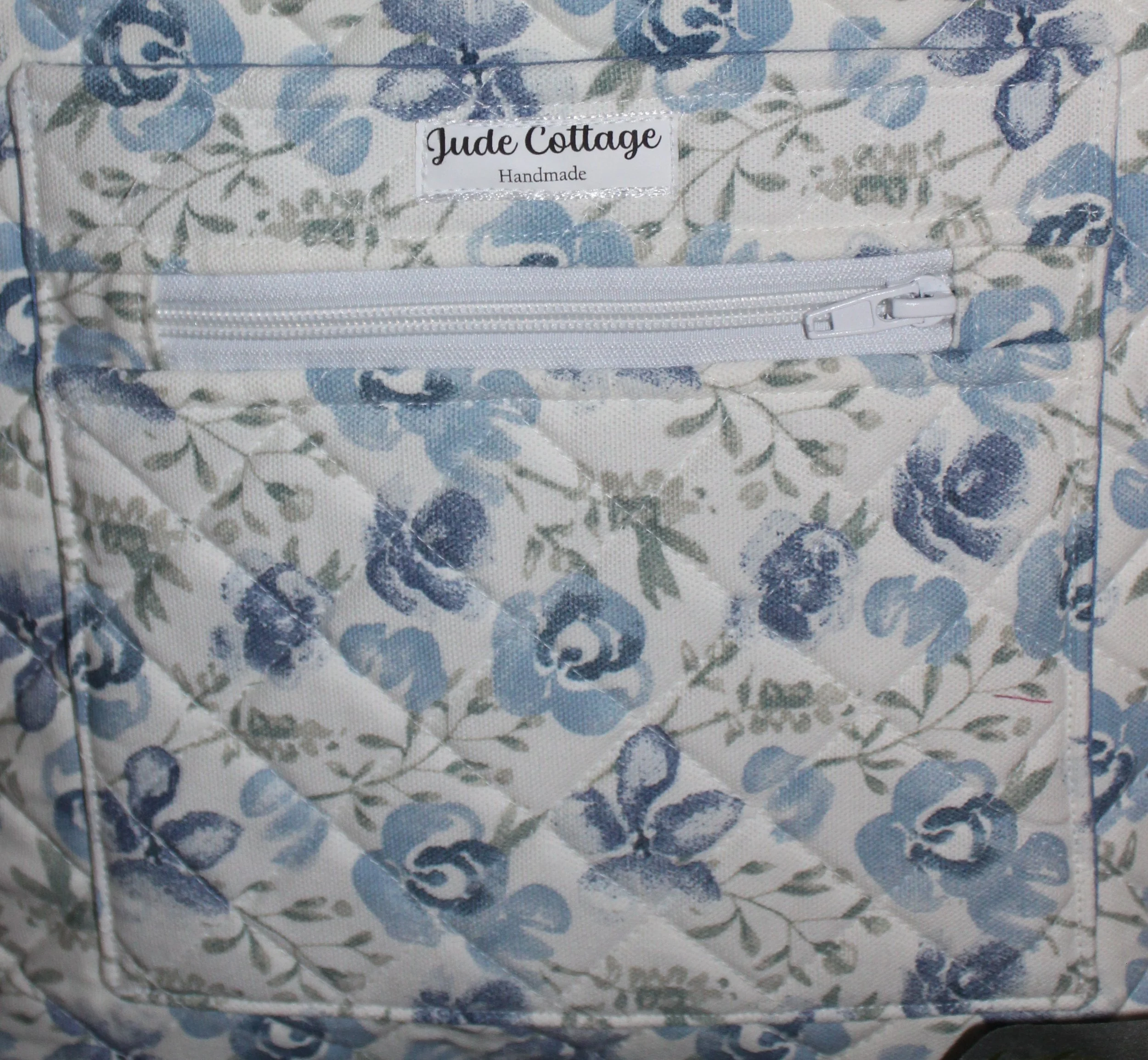 Up‑close front view of the Elise quilted tote, showing the exterior slip pocket and exterior zip pocket along with the quilted pattern.