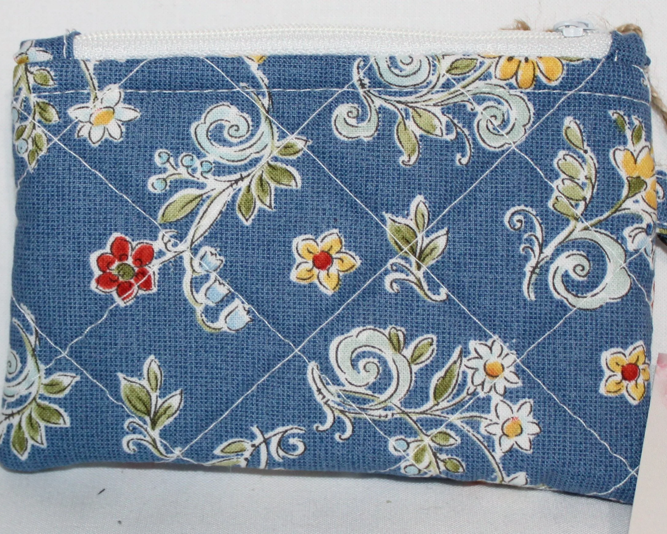 Up-close view of the Liberty Blue quilted keychain wallet with a summer floral pattern, zipper closure, and metal key ring.”