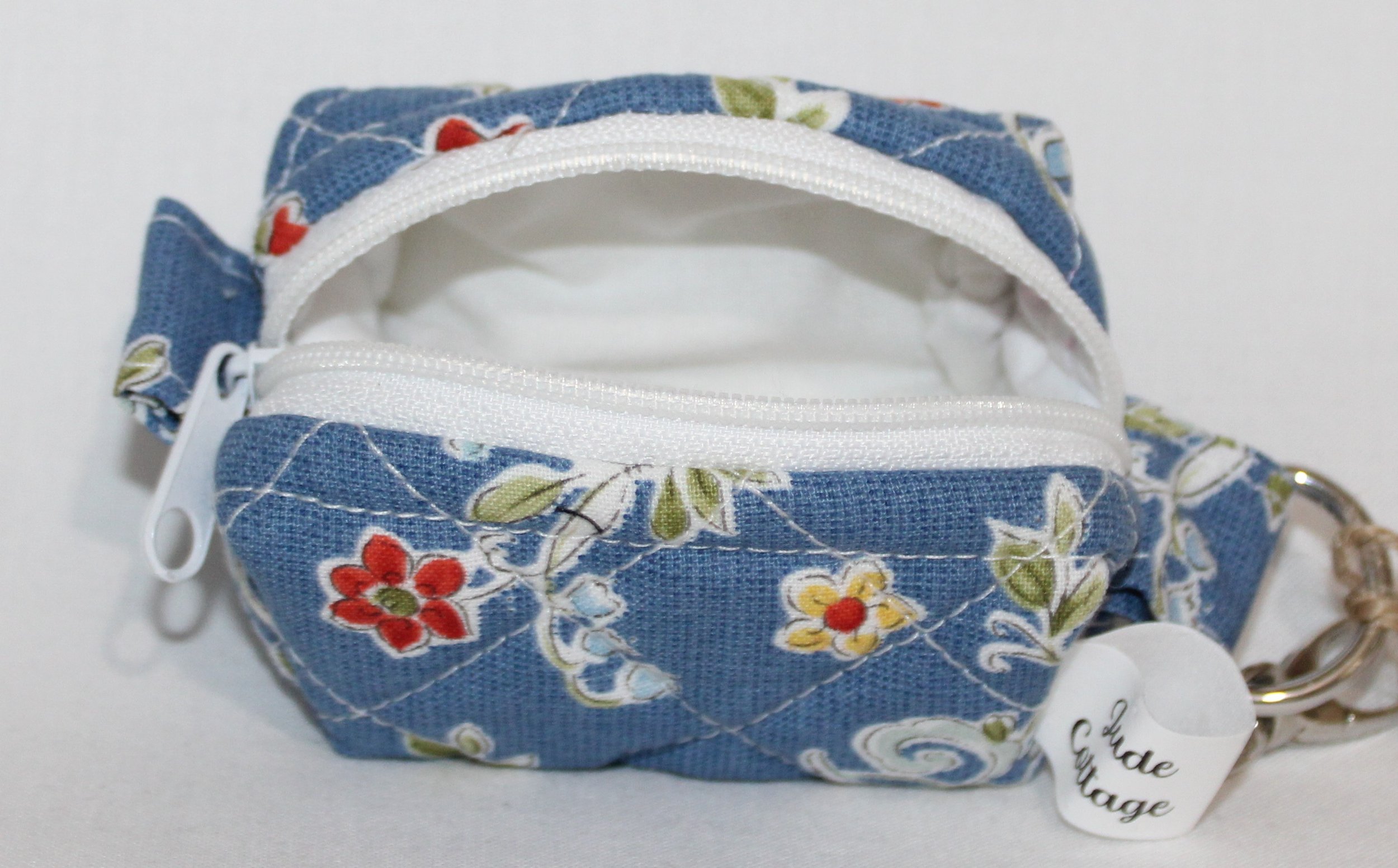 Open top view of the Liberty Blue Bag Charm featuring a blue background with red and yellow floral print, showing inside white lining and zip enclosure.
