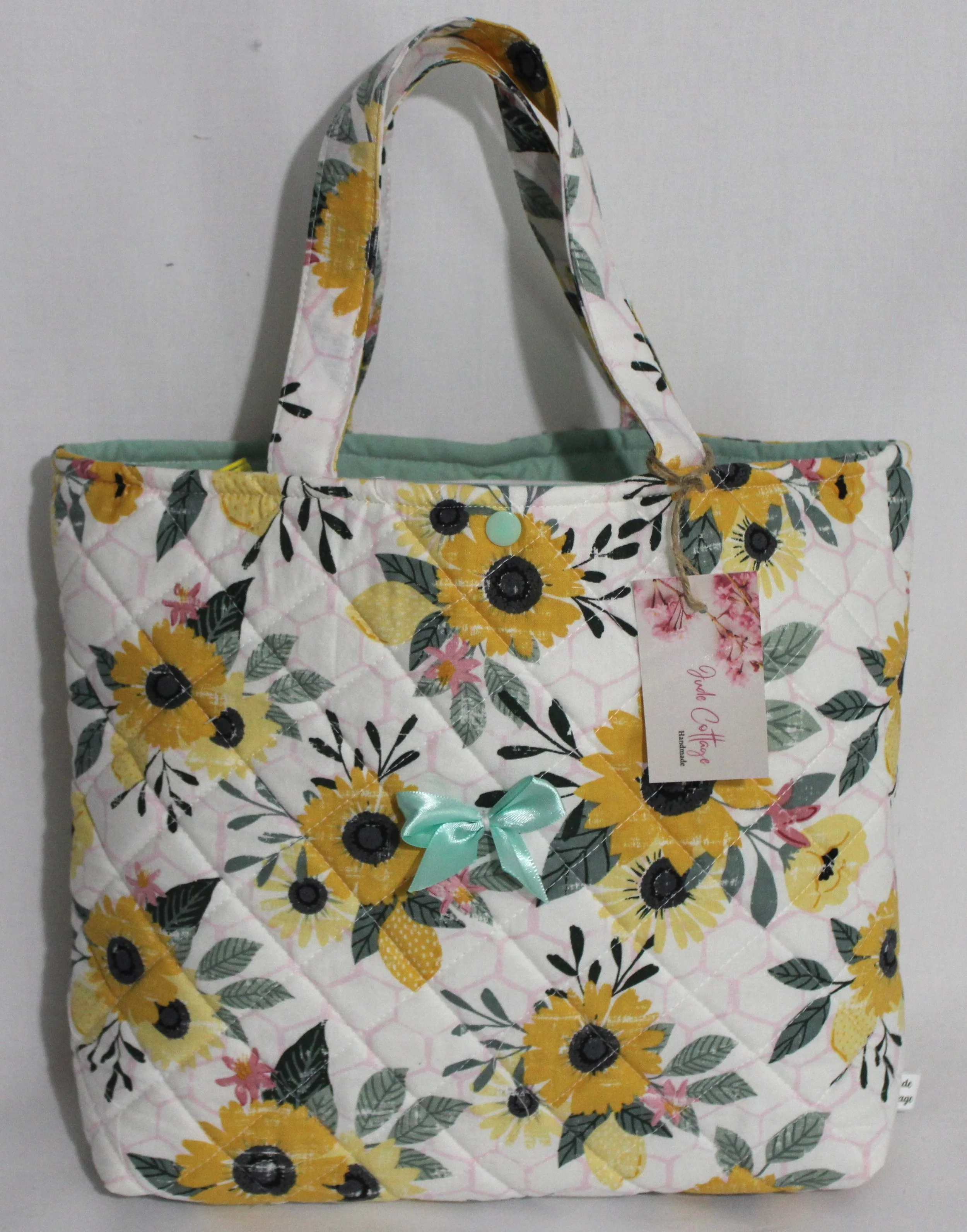 Front view of the Honeycomb Sunflower quilted Bible sleeve with sunflower fabric and a small green bow on the front.