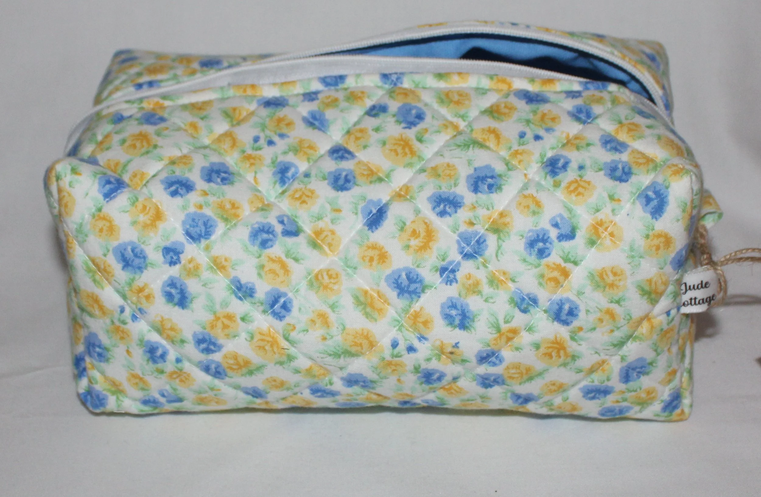 Front view of the Melody floral quilted travel pouch with blue and yellow flowers on a white background.