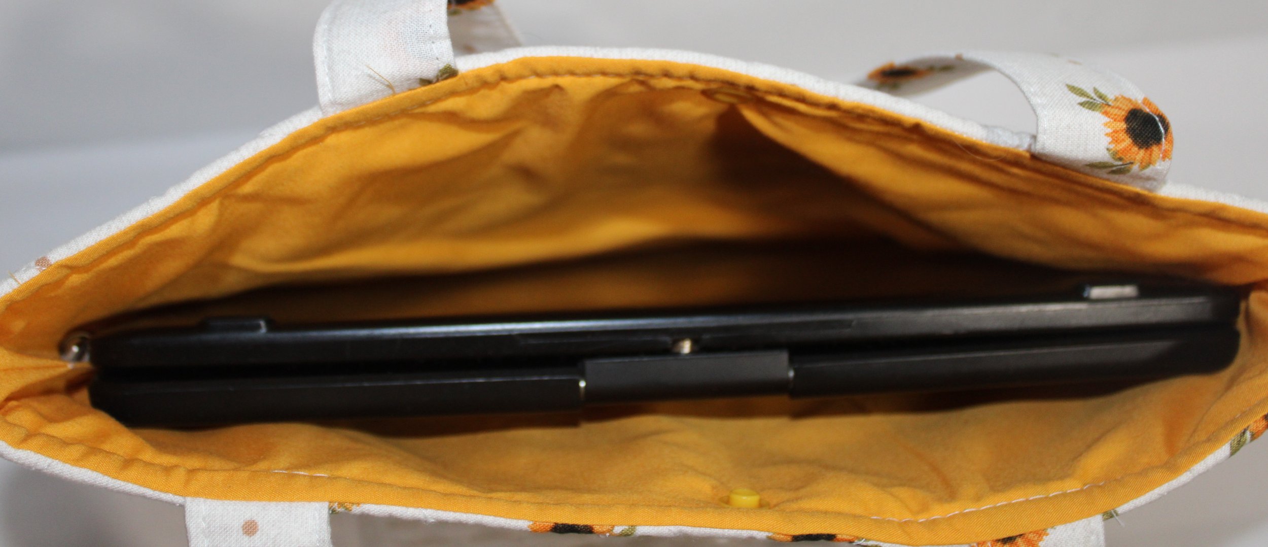 Top view of the Sunflower Medley quilted tablet and book sleeve, showing a tablet inserted and the gold lining visible.