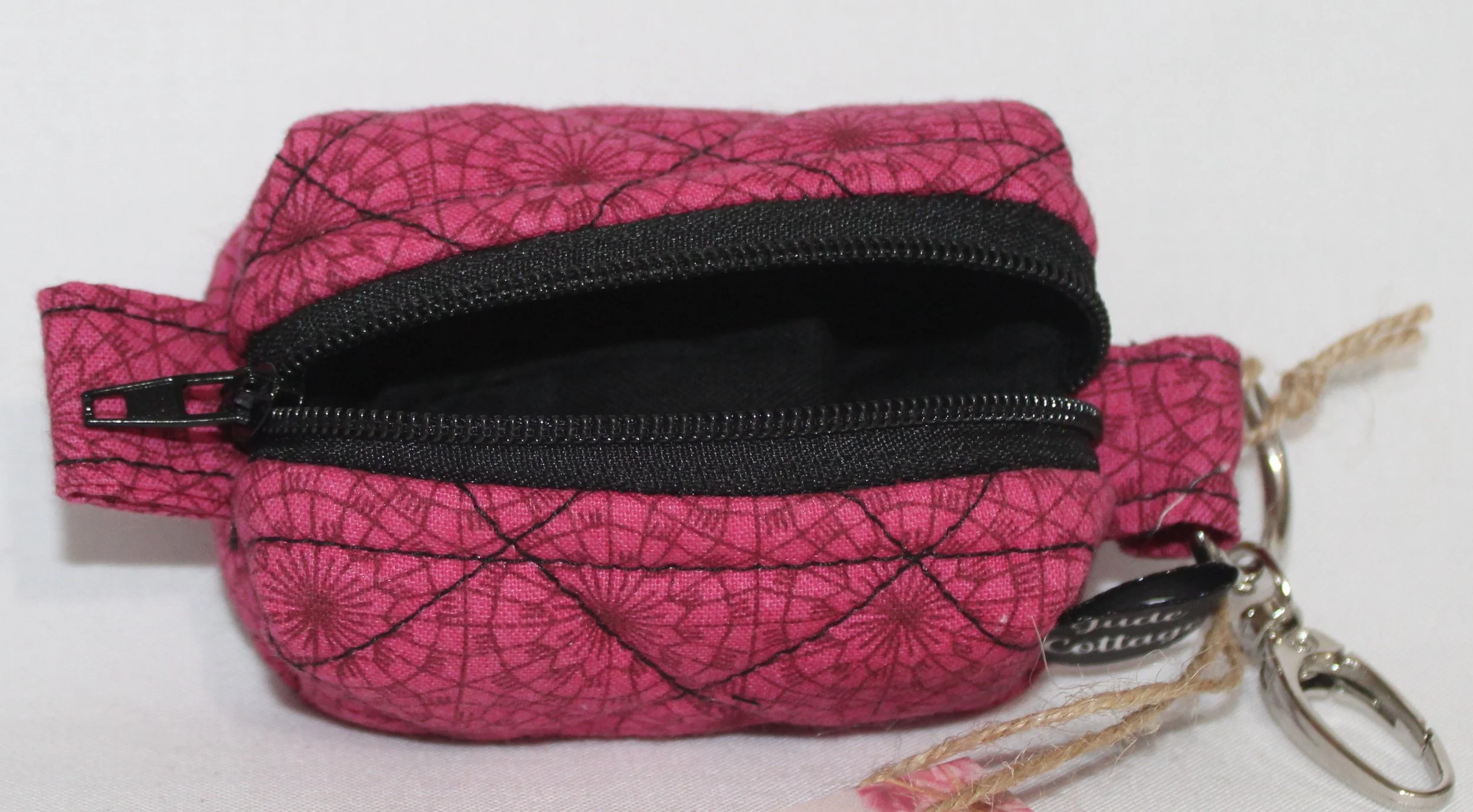 Open top view of the Claire Bag Charm showing the black zip enclosure and black lining on a dark pink  background with black geometric print fabric.