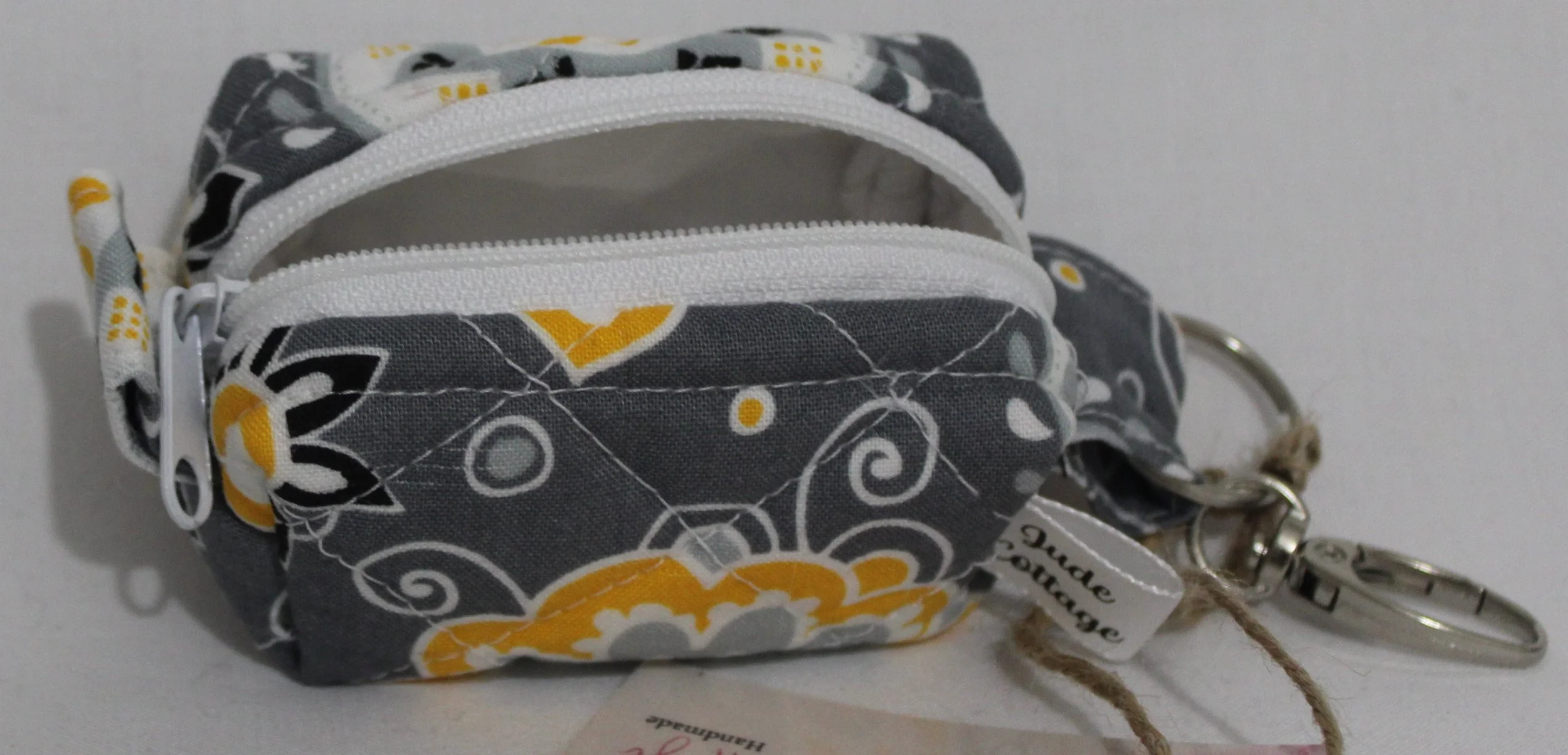 Top open view of the Medallion Bag charm featuring gray fabric with black, white and yellow floral print, showing white lining.
