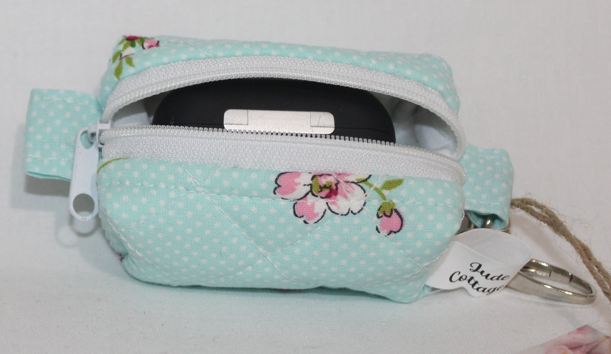 Top open view of the Blossom Bag Charm featuring a light blue polka dot fabric with pink cherry blossom print shown with an Airpod Pro earbud case inserted for sizing reference.
