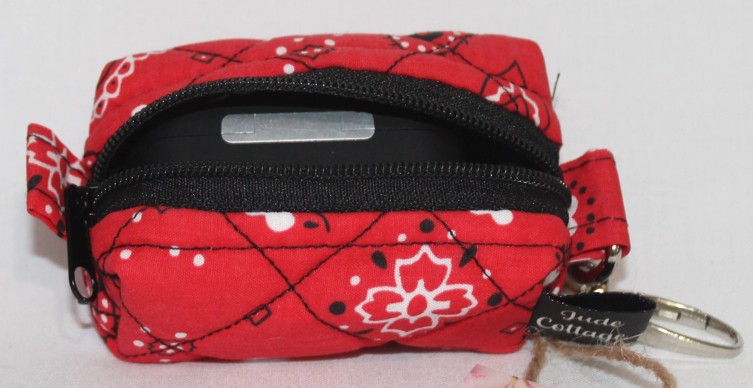 Top open view of the Red Bandana Bag Charm showing bandana print fabric with a set of Airpod Pro earbuds inserted for size reference.