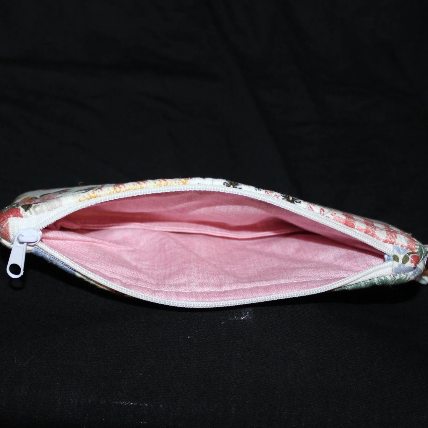 Top open view of the Serenity Large Keychain Wallet showing white zip closure and pink linen print lining.