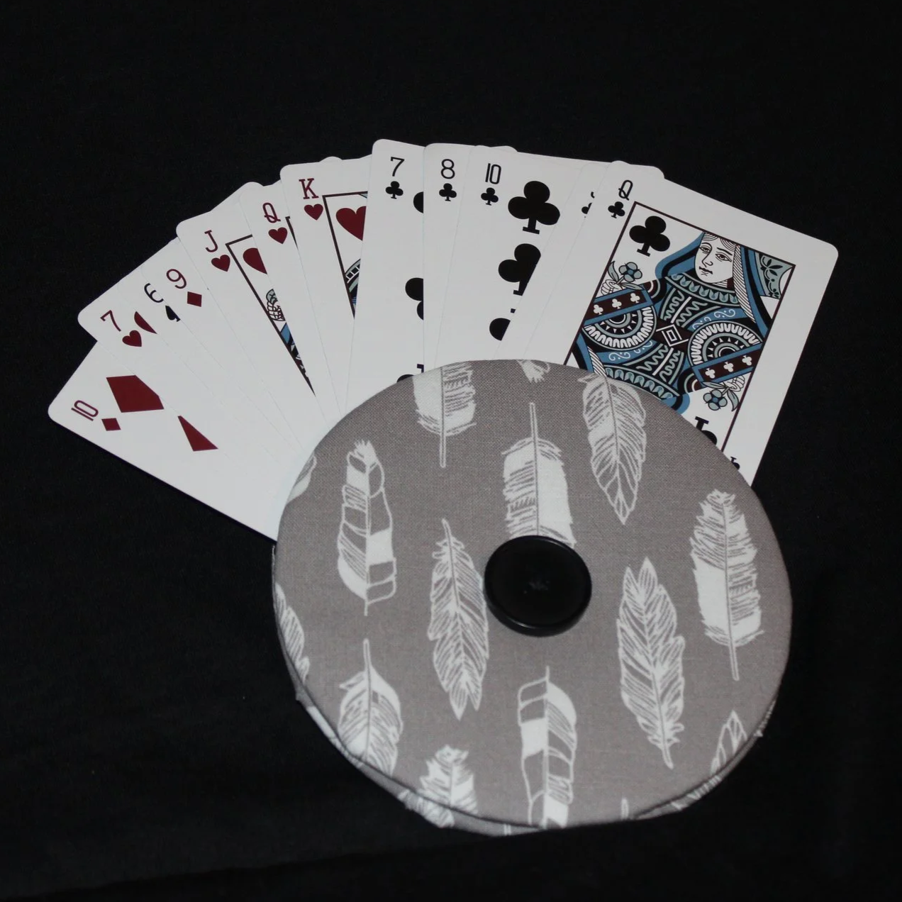 Front view of the Grey Feather Card Holder featuring a grey background with white feather motif print fabric shown in use with an array of playing cards.