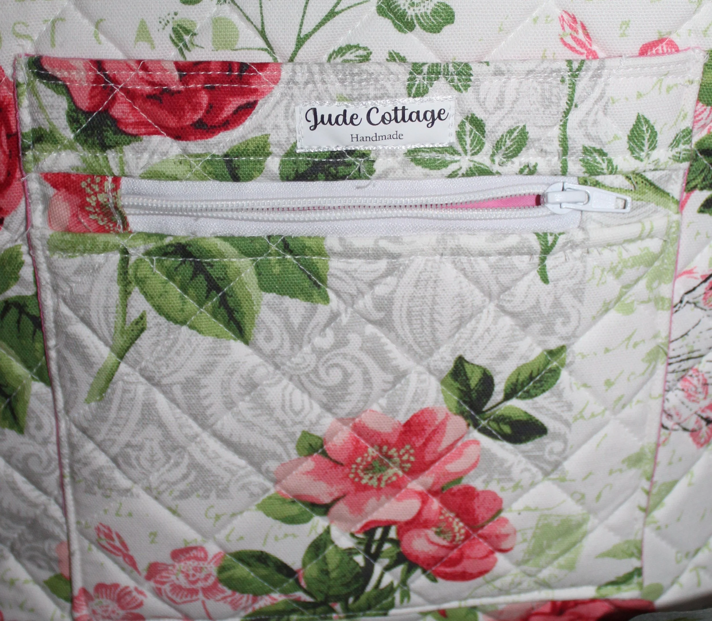 Up‑close view of the front pockets of the Colette quilted tote, showing one exterior slip pocket and one exterior zip pocket, along with the quilted pattern.