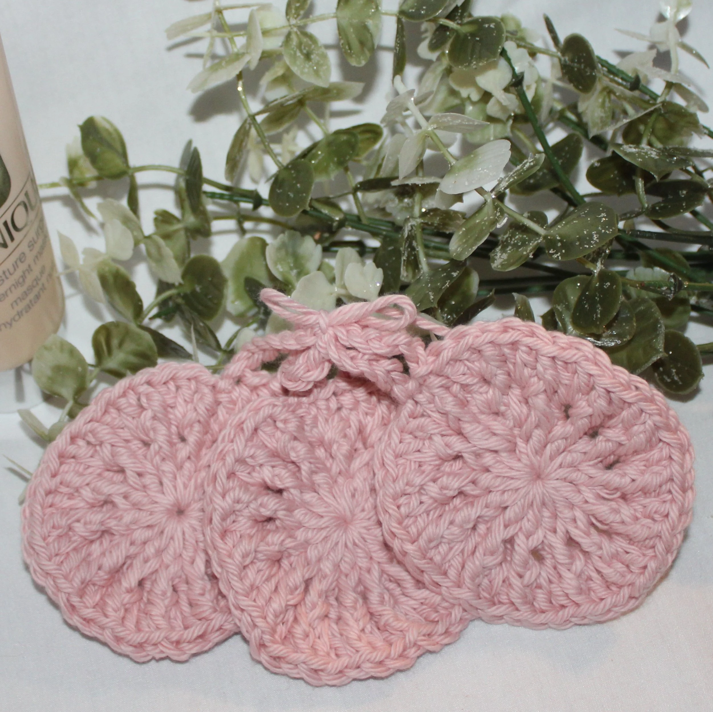 Close‑up of round crocheteink facial scrubbies with a textured stitch pattern showing a set of three.