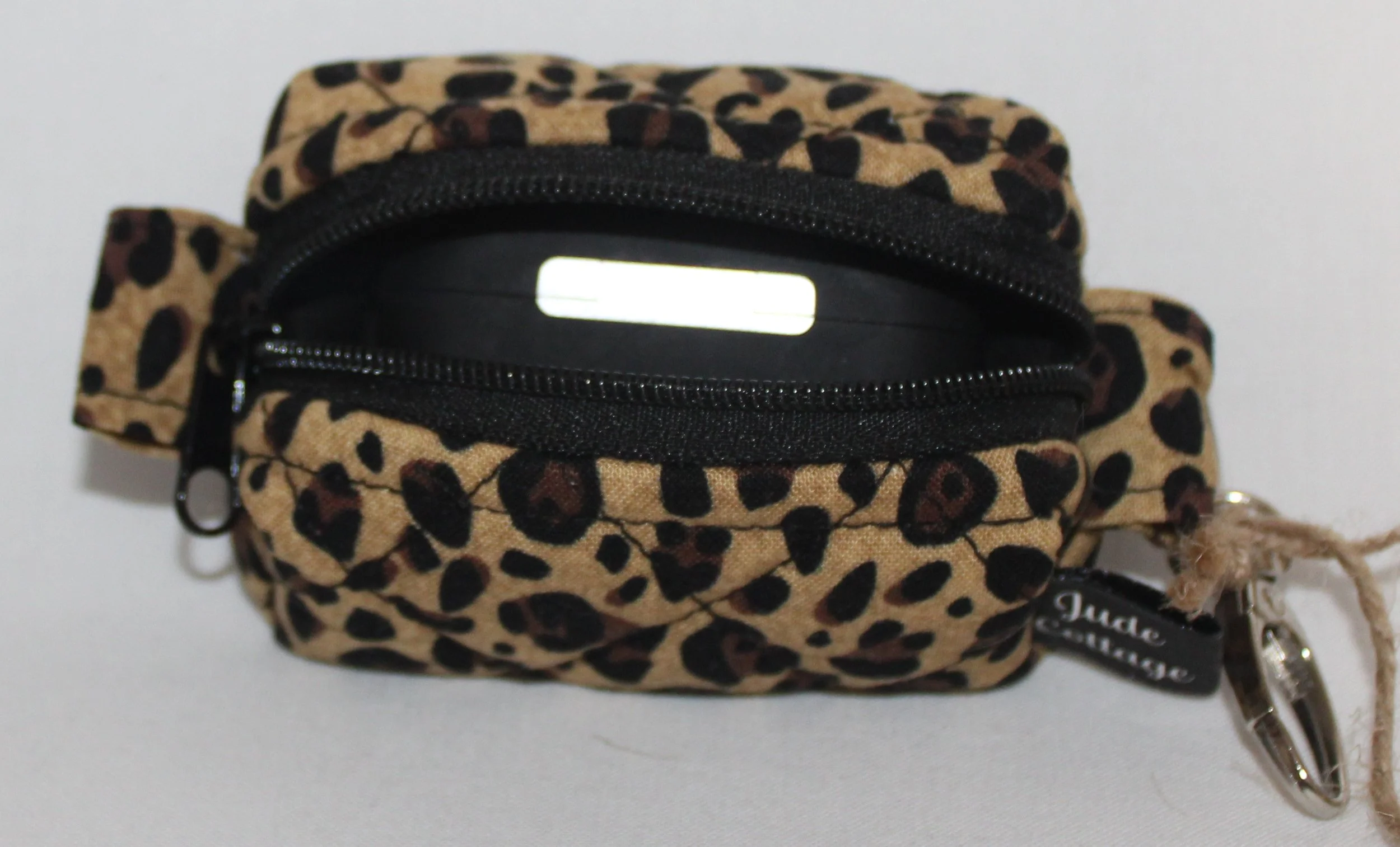 Top open view of the Sahara Bag Charm featuring cheetah print fabric with a set of Airbud Pro earbuds inserted for size reference.