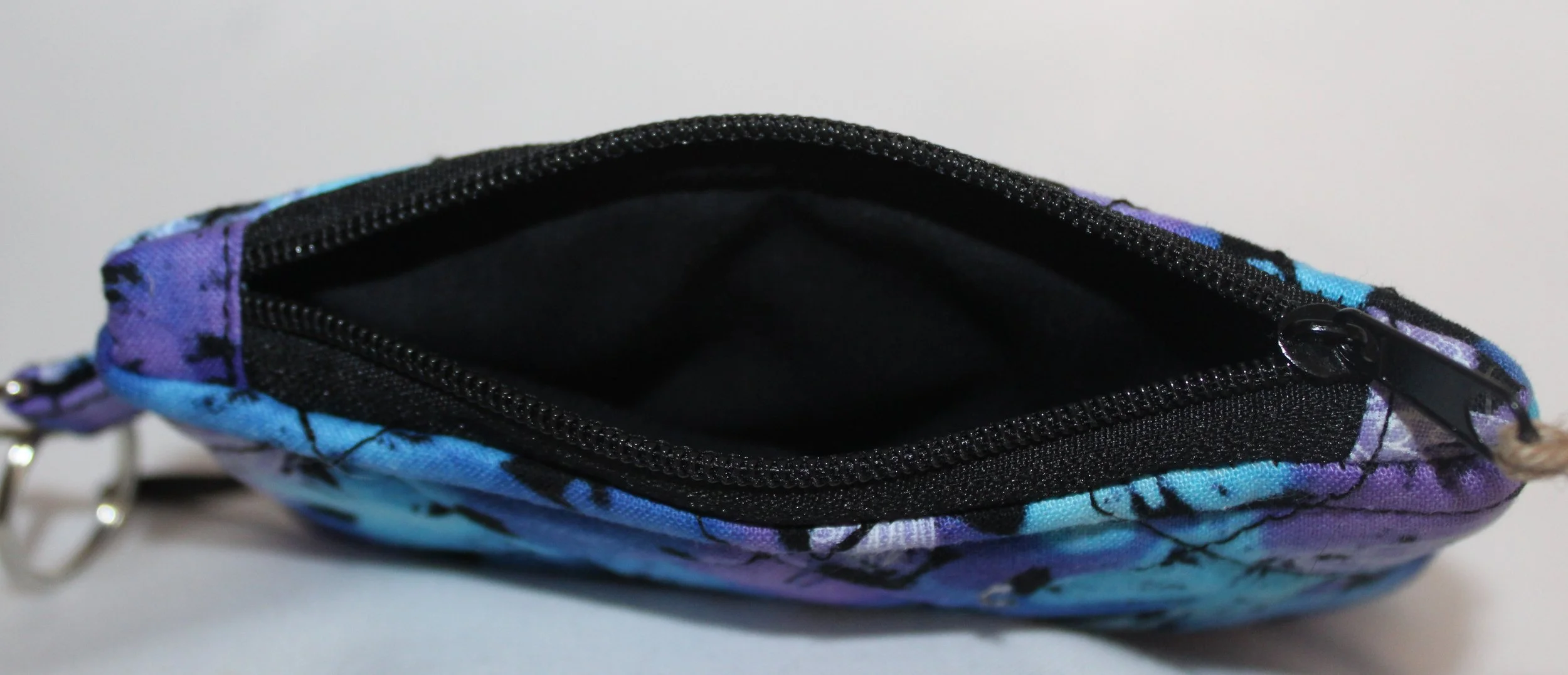 Top view quilted keychain wallet with mist‑toned butterfly pattern, zipper closure, and metal key ring.