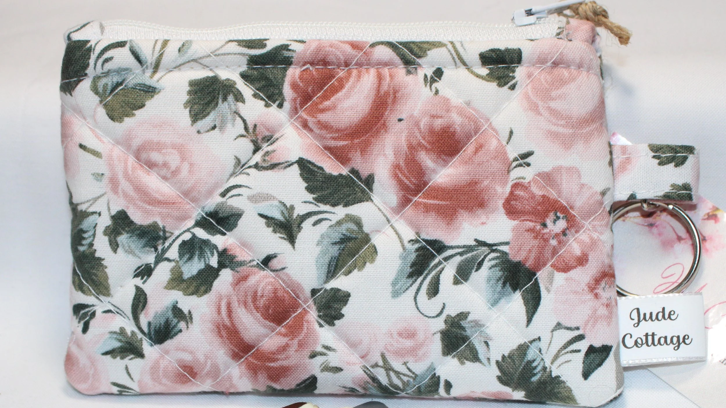 Quilted keychain wallet with rose garden floral pattern, zipper closure, and metal key ring.