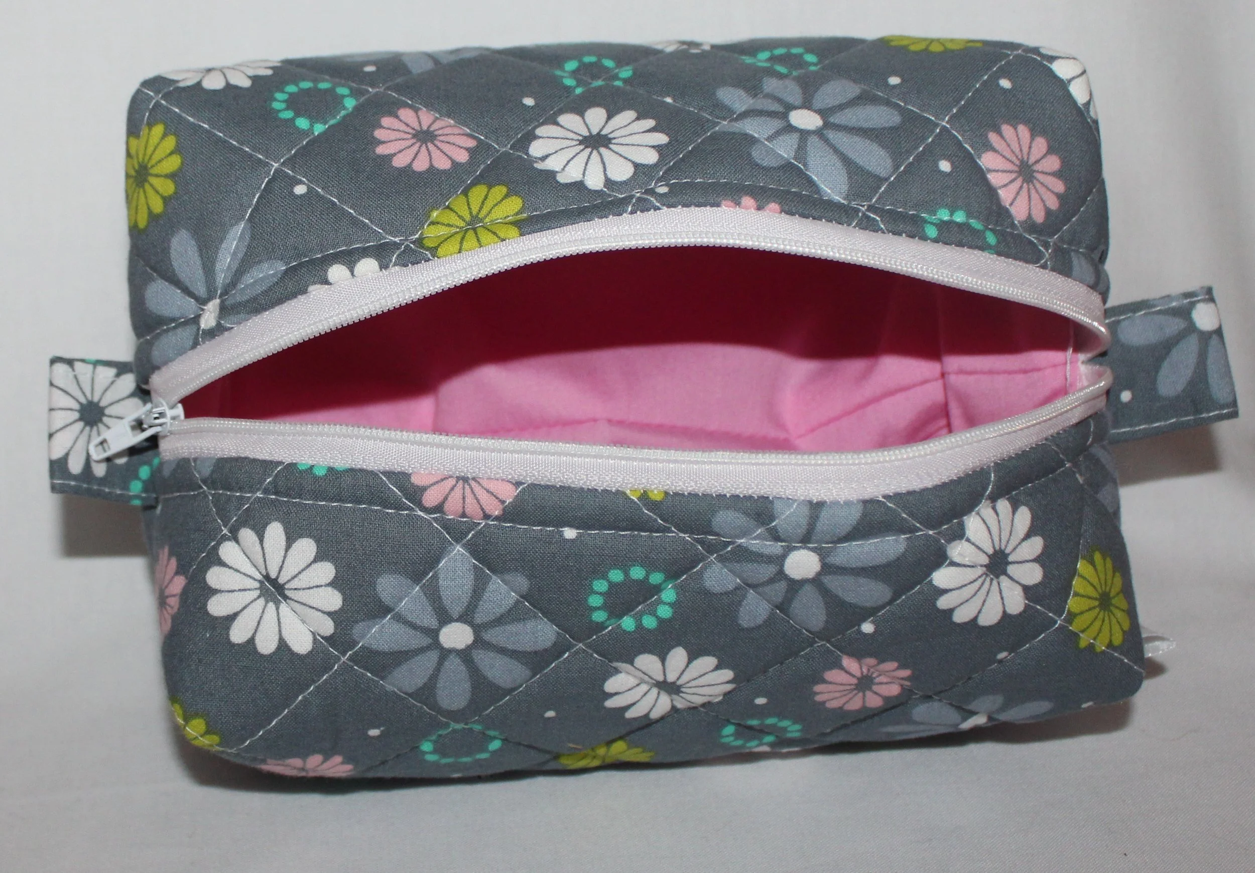 Top open view of the Phoebe quilted travel pouch showing the white zipper and pink lining.