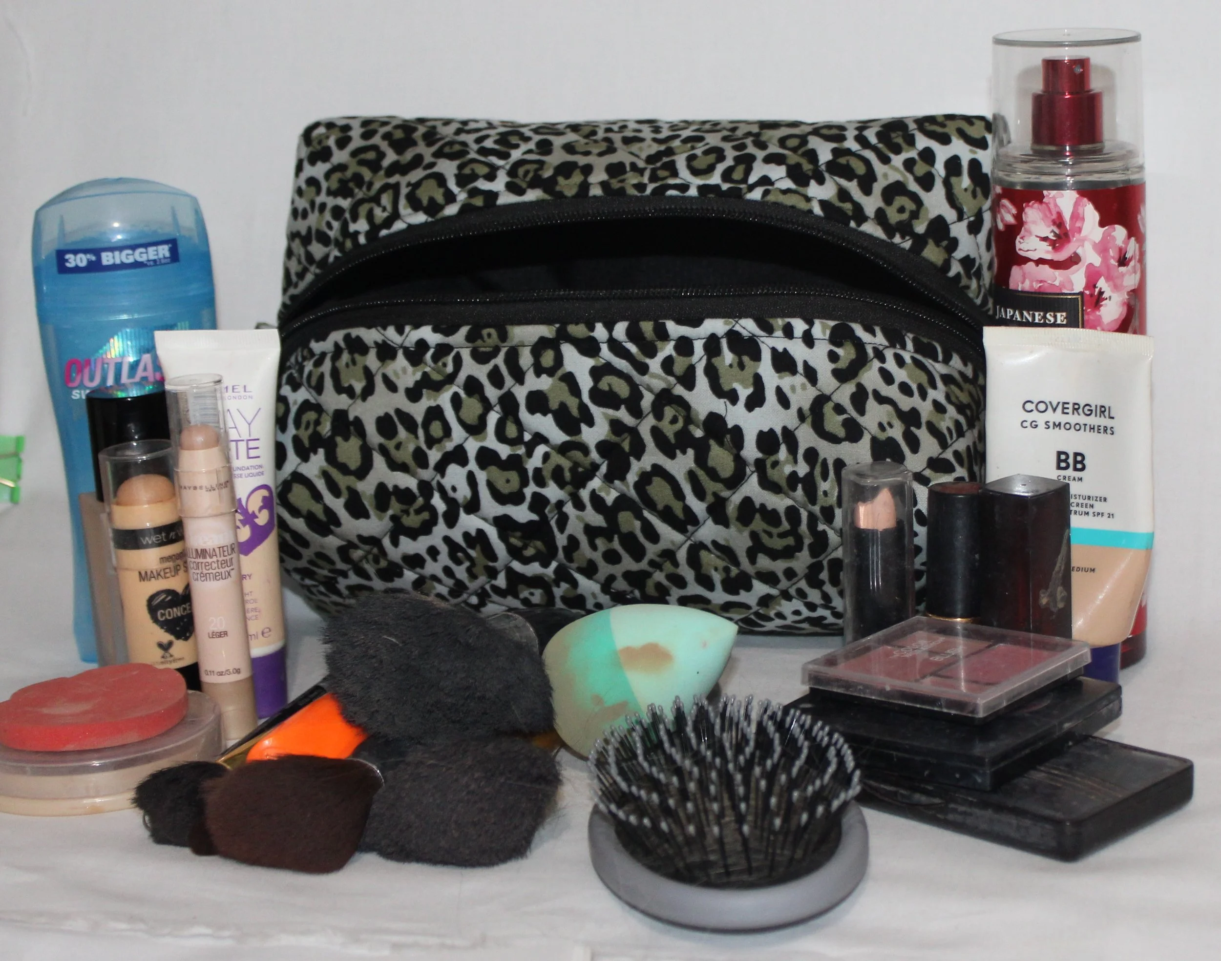 Angled front view of the Diana quilted travel pouch shown with cosmetics to illustrate size.