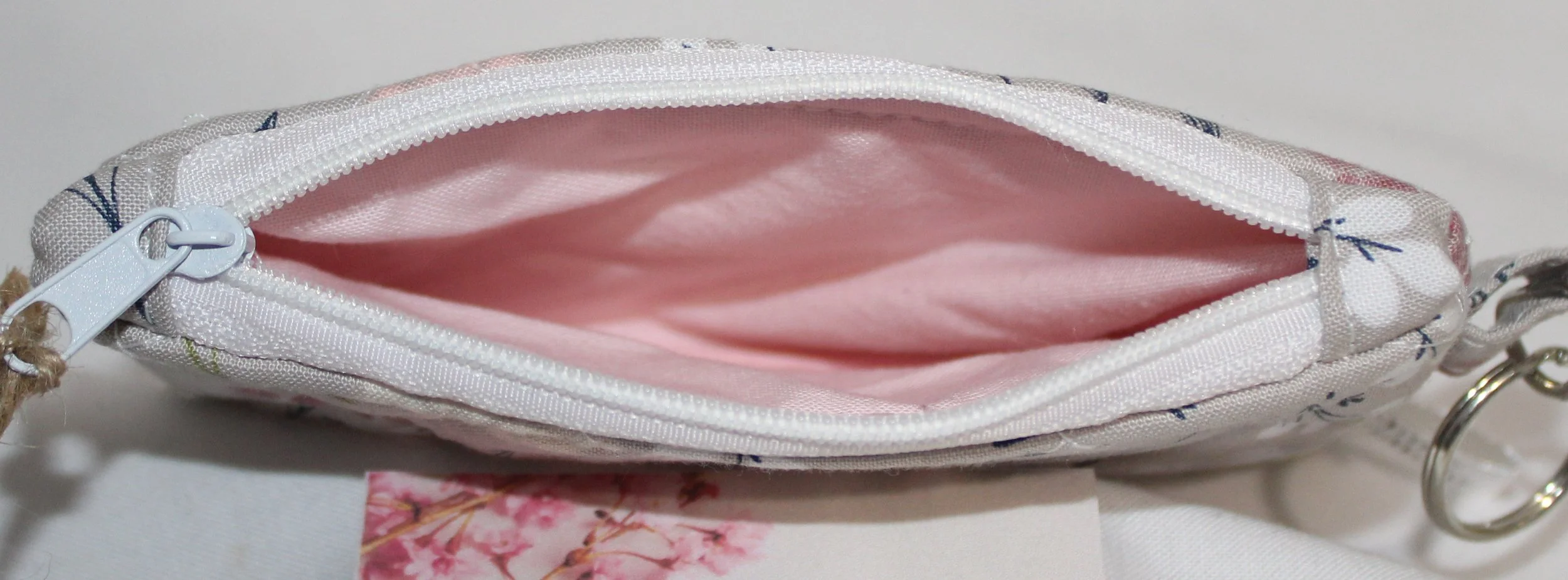 Top view of Dandelion Field quilted keychain wallet showing the white zipper and light pink lining.