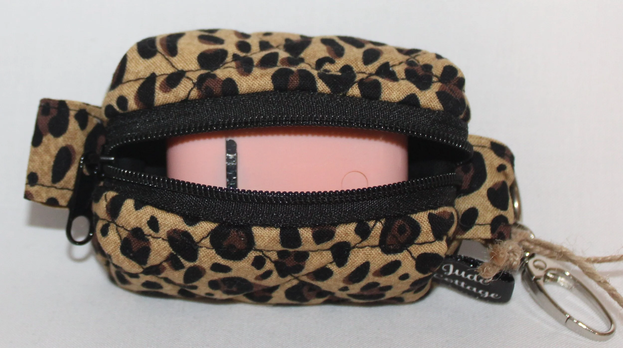 Top open view of the Sahara Bag Charm featuring cheetah print fabric with a set of Airbuds inserted for size reference.