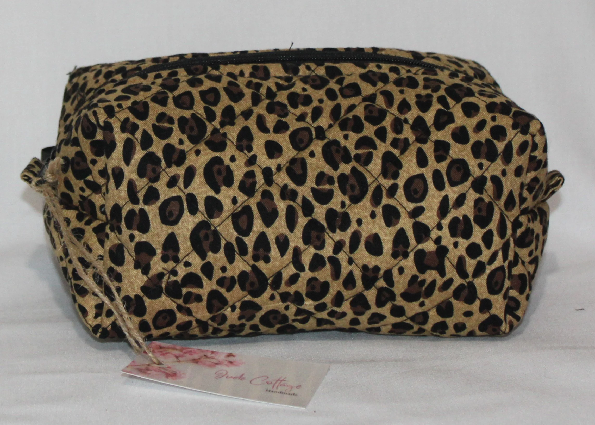 Front view of the Sahara quilted travel pouch showing the neutral cheetah‑print exterior.