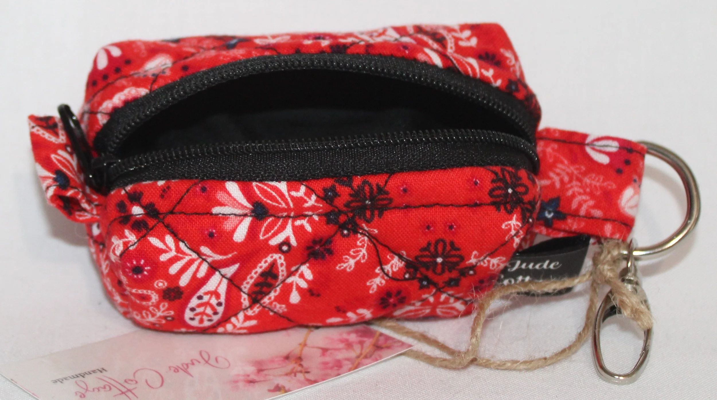 Top open view of the Freedom Red Bag Charm featuring red background with floral and paisley print fabric, showing black lining and zip enclosure.
