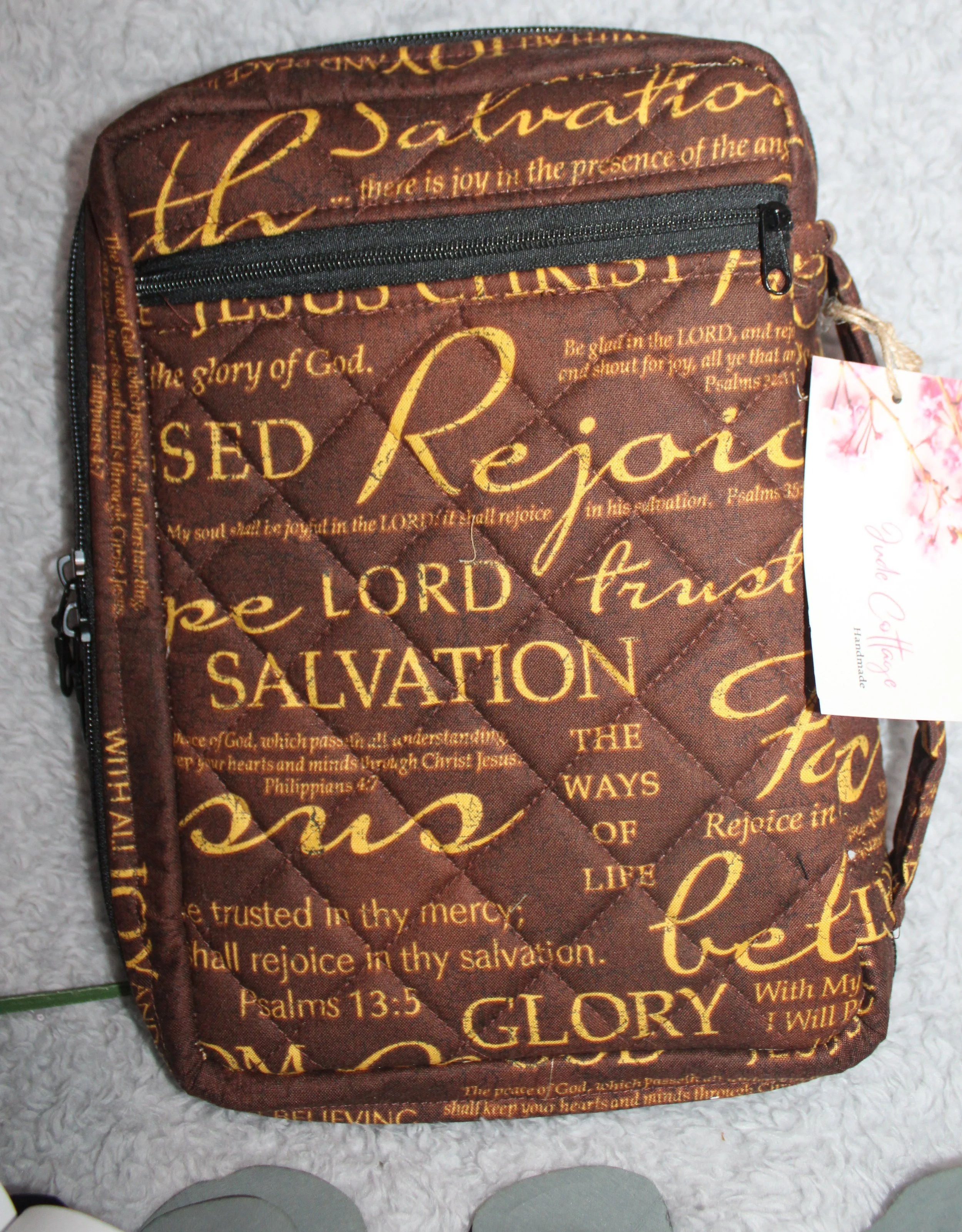 Back view of the Rejoice Bible Study Case showing the zippered exterior pocket on the brown quilted cover with gold inspirational religious wording.