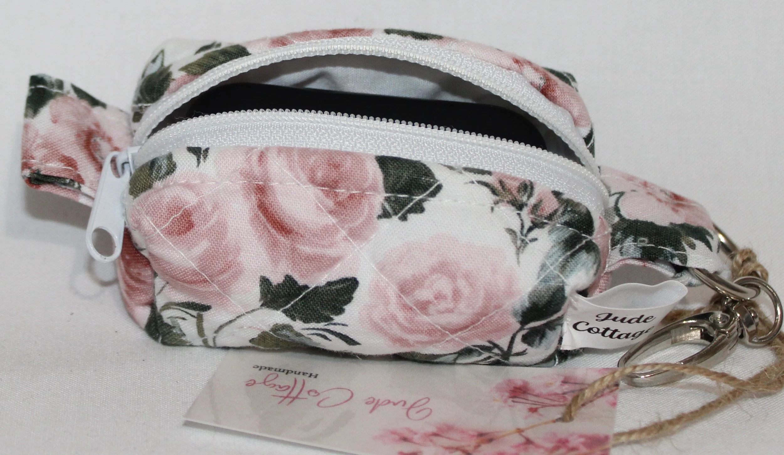 Open top view of the Rose Garden Bag Charm featuring white fabric with pink rose print shown with a J Lab earbud case inserted for size reference.